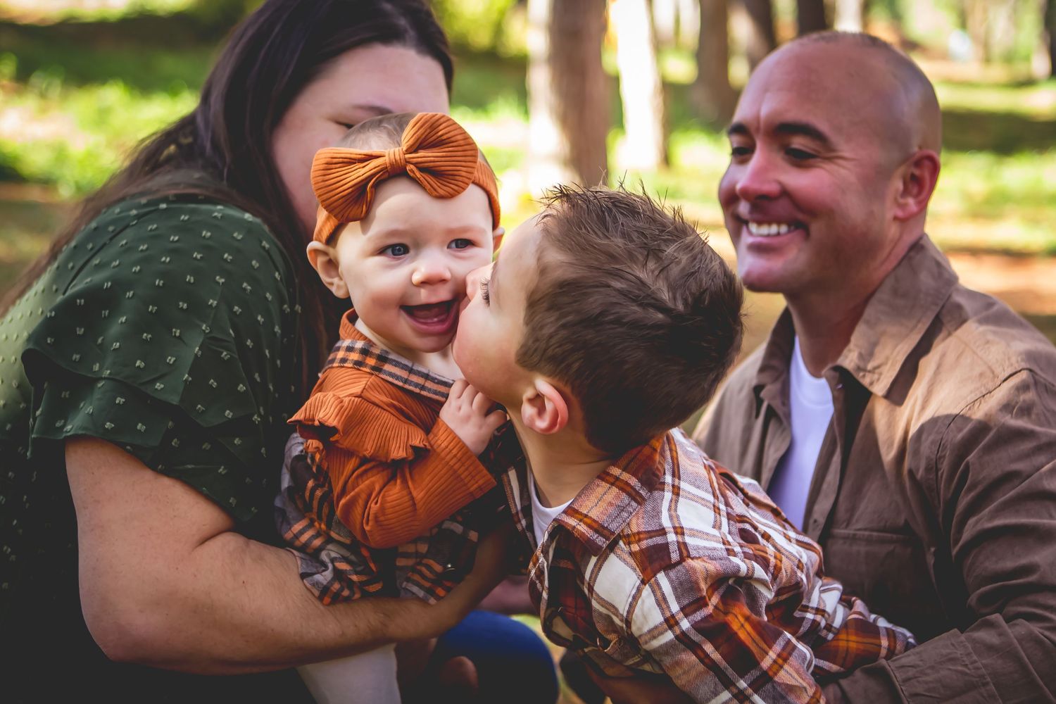 A joyful family moment captured outdoors with laughter and smiles in a sunlit park setting at Retzer Nature Center in Waukesha.