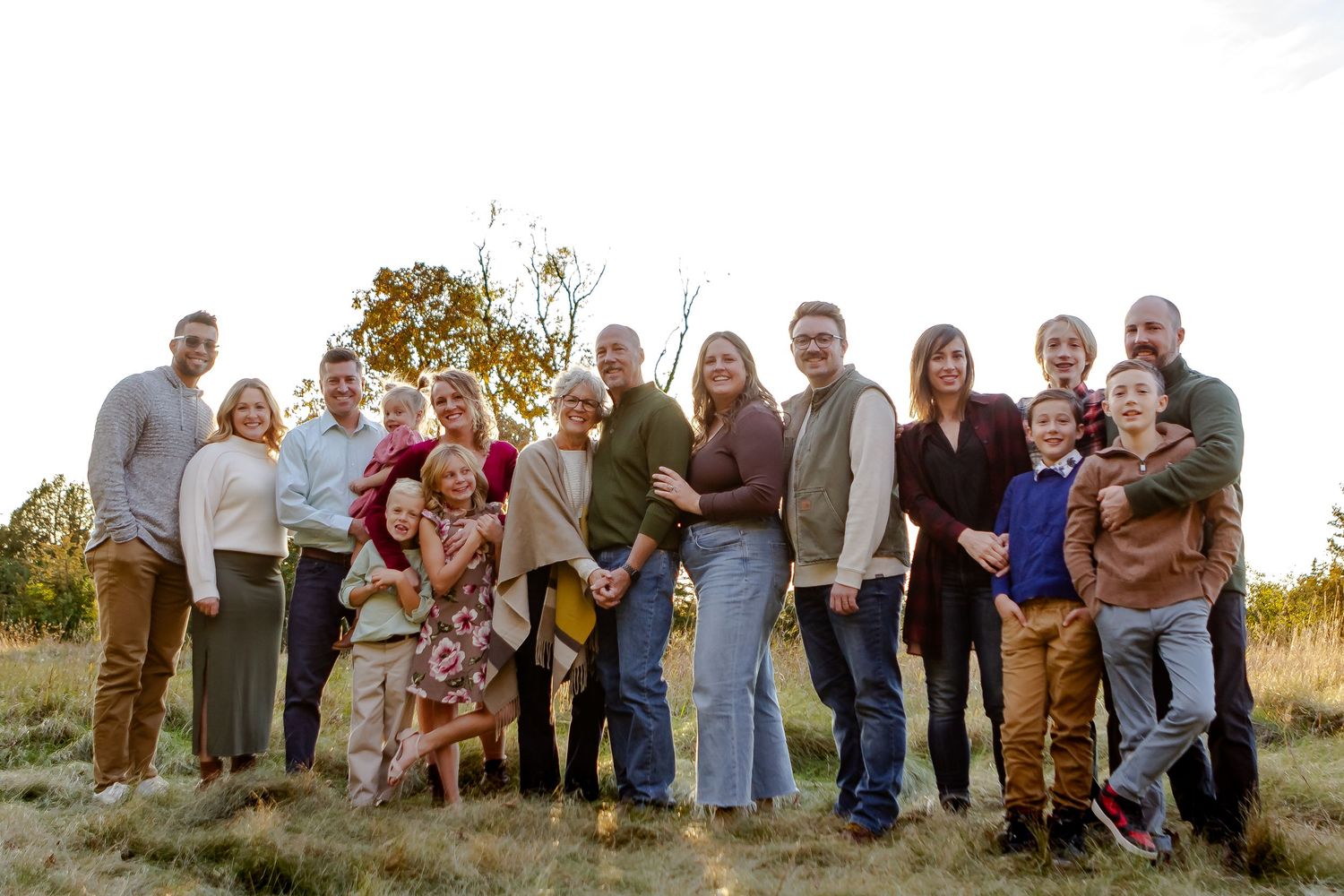 Extended family smile in field during fall photo session in Oconomowoc