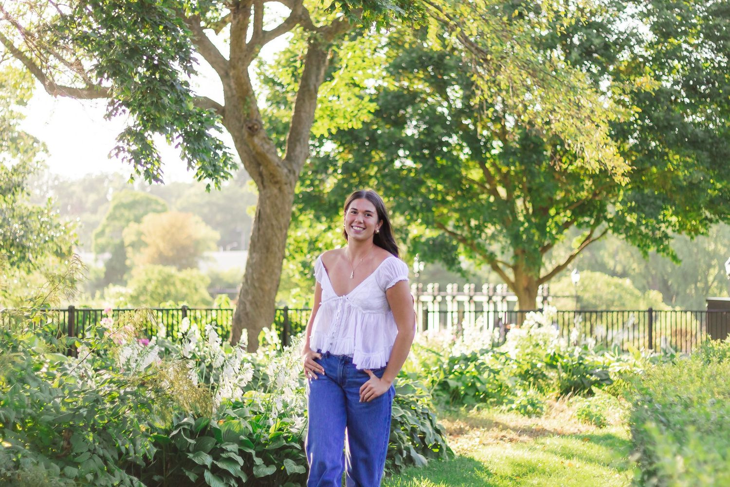 Outdoor portrait session in front of a rustic wooden fence with green foliage in the background.