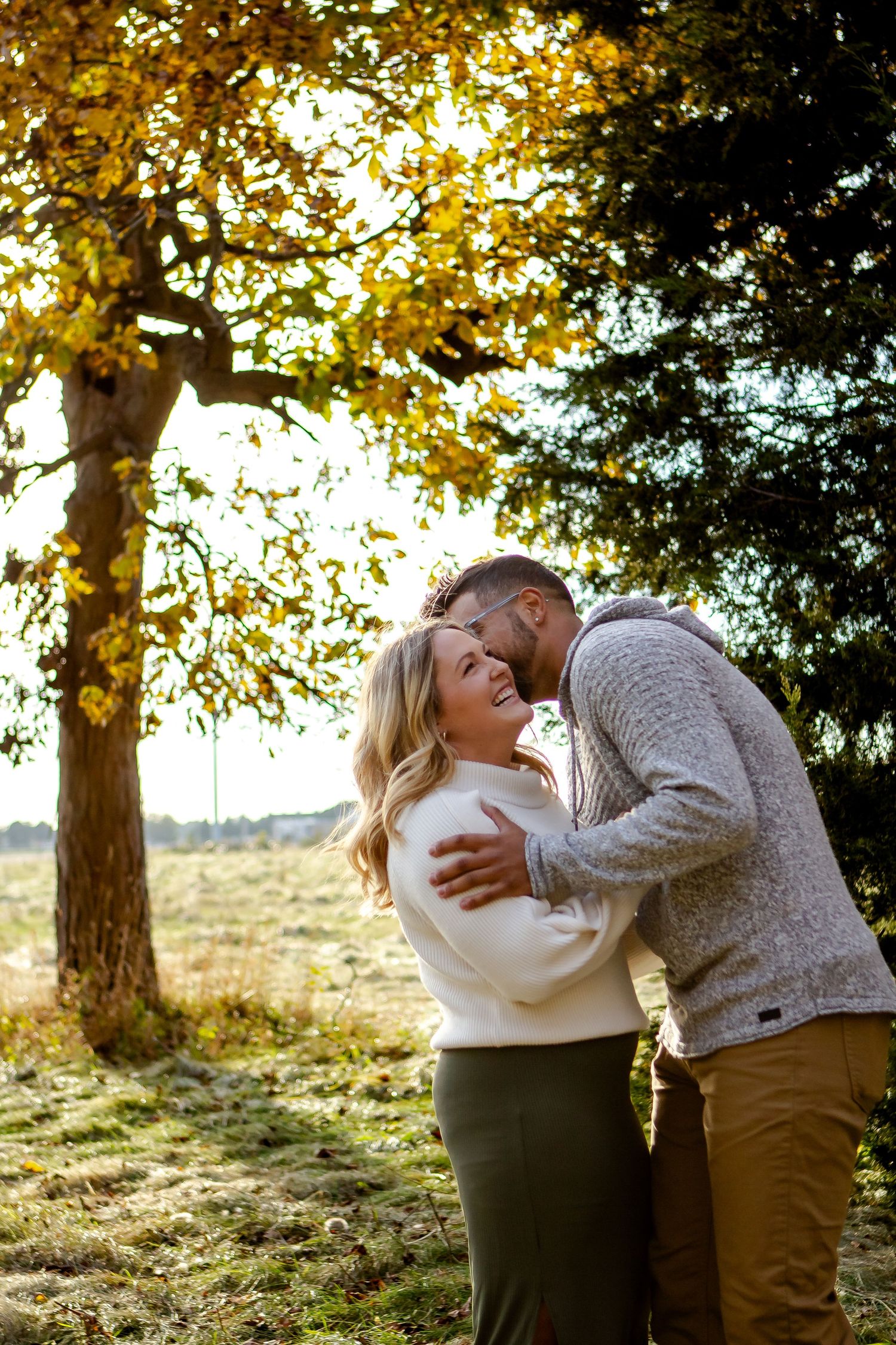 A man kisses his significant other while she laughs during fall photo session in Oconomowoc