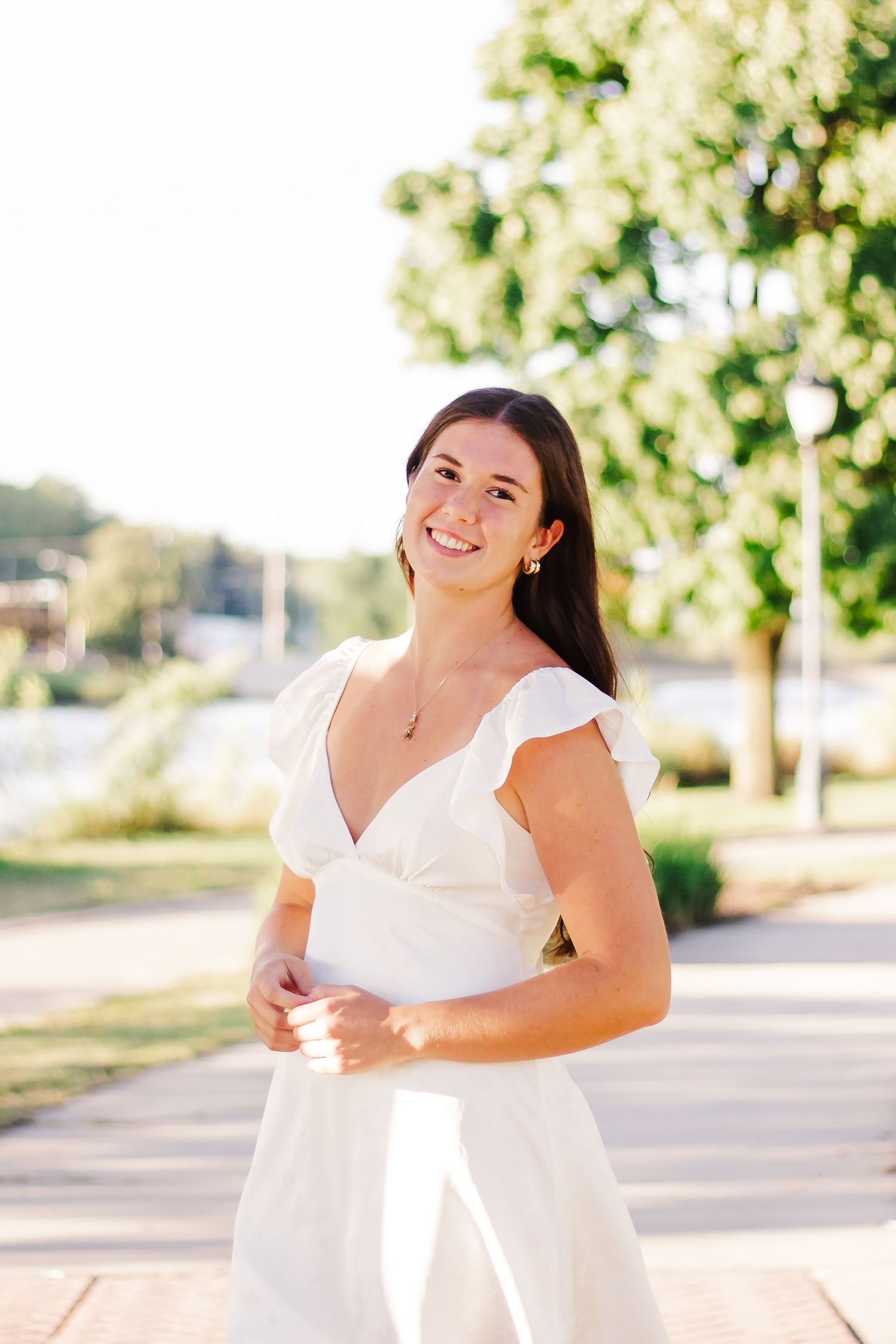 Sunlit outdoor photoshoot on a paved pathway with trees providing natural shade.