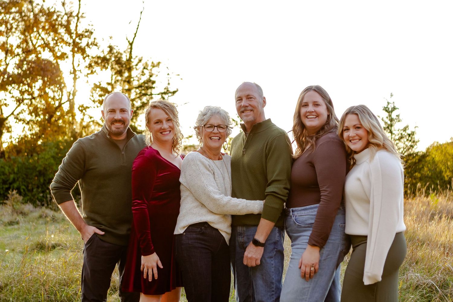 Family poses together in field during fall photo session