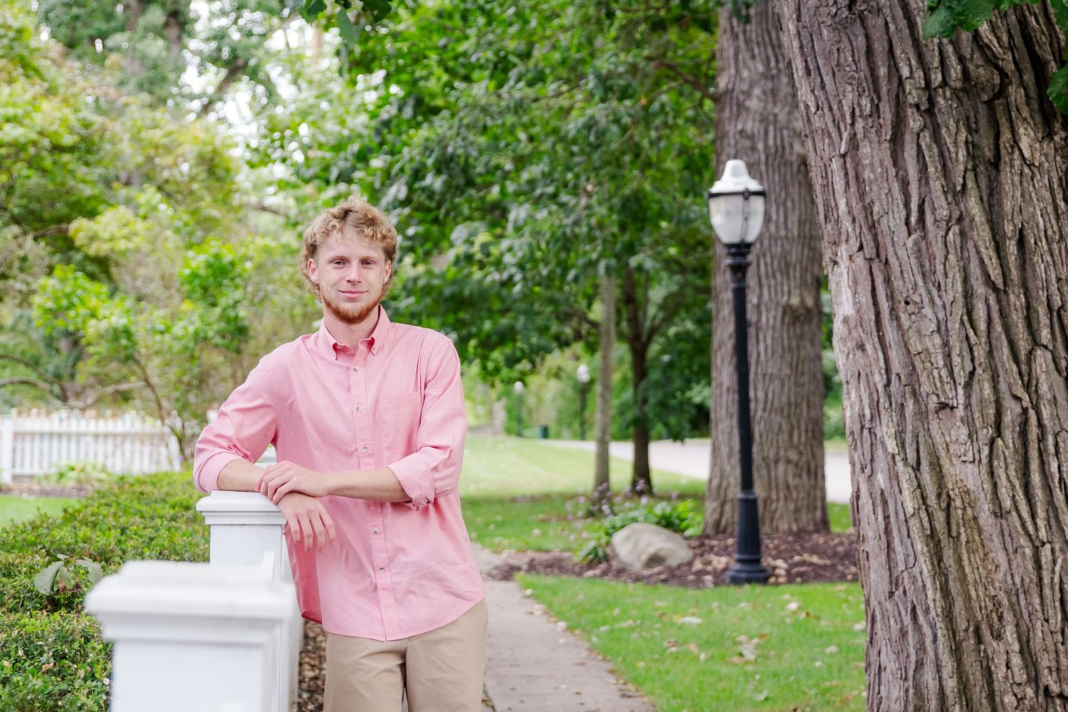 Portrait session in garden setting with pink shirt against natural backdrop.
