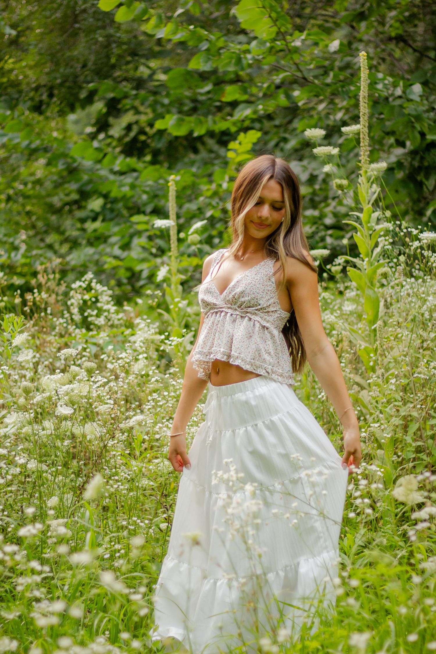 White dress flowing among wild daisies and summer meadow flowers.