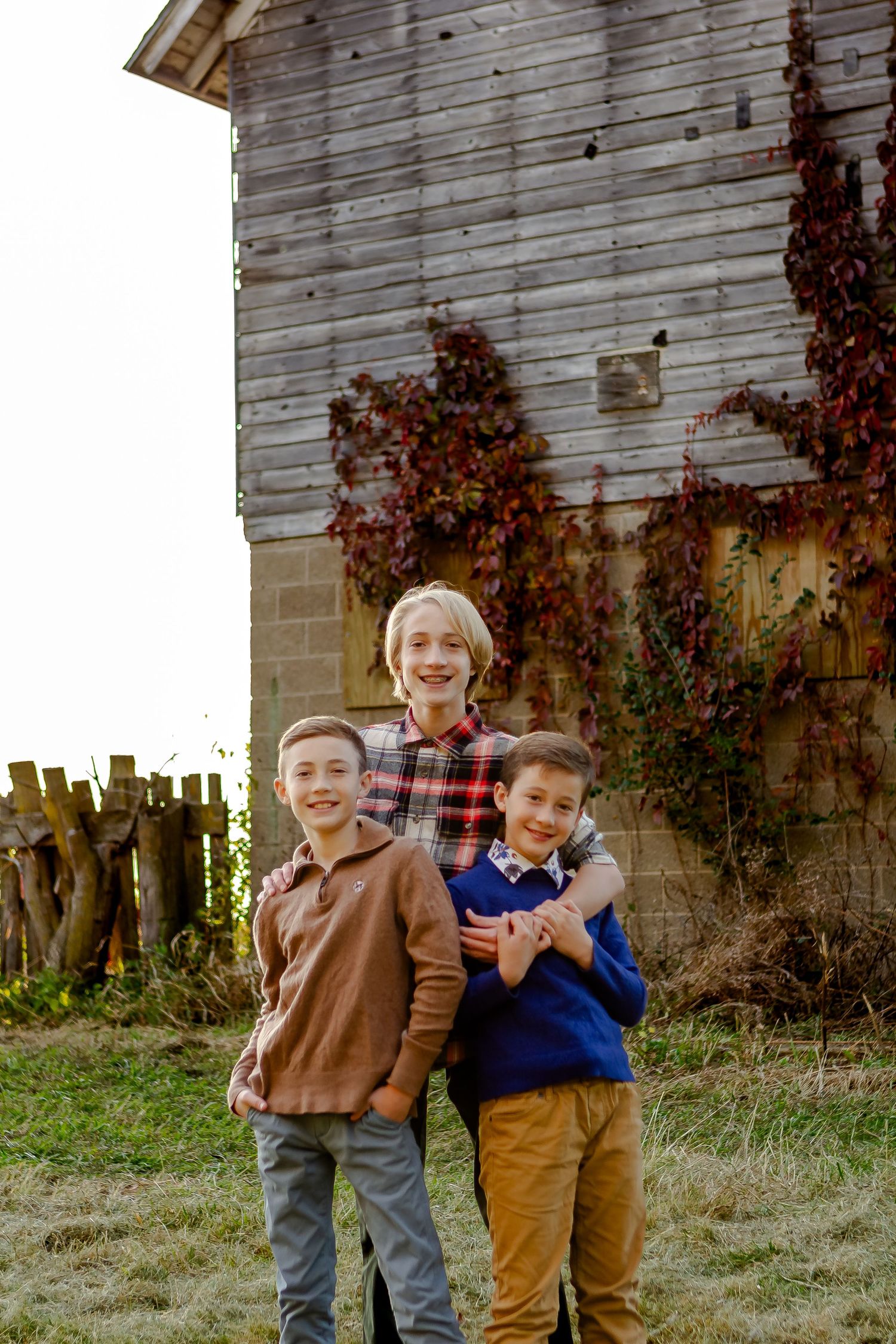 Three brothers pose outside of barn during fall photo session in Oconomowoc