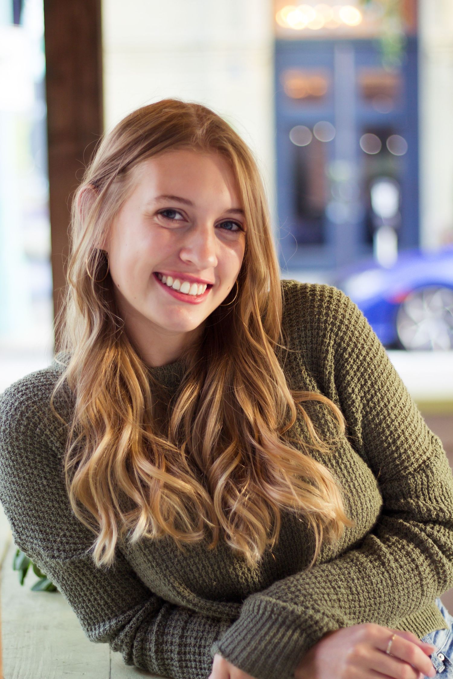 Casual portrait in an olive green sweater against a blurred background.