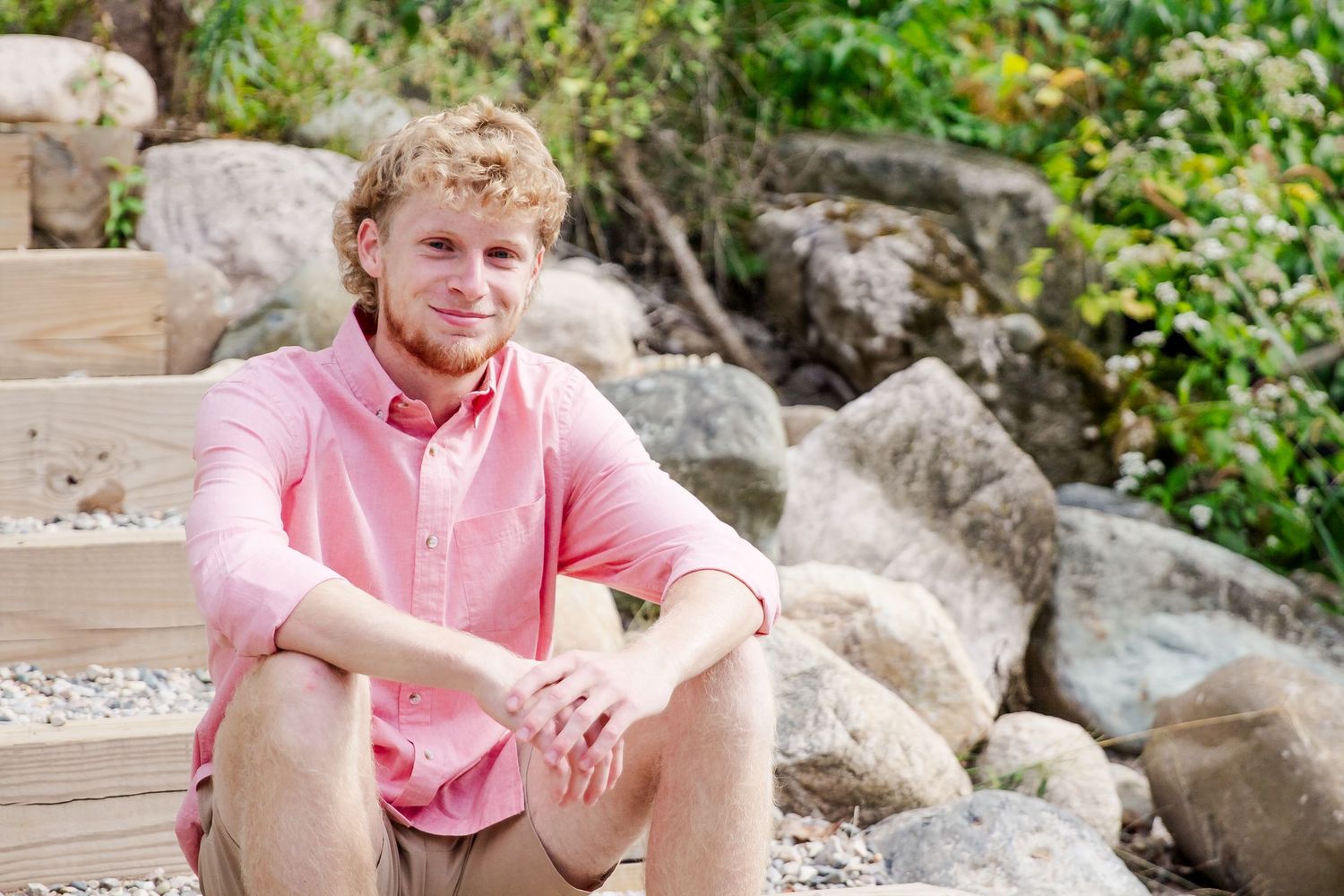 Casual outdoor portrait among rocks and landscaping in summer garden setting.