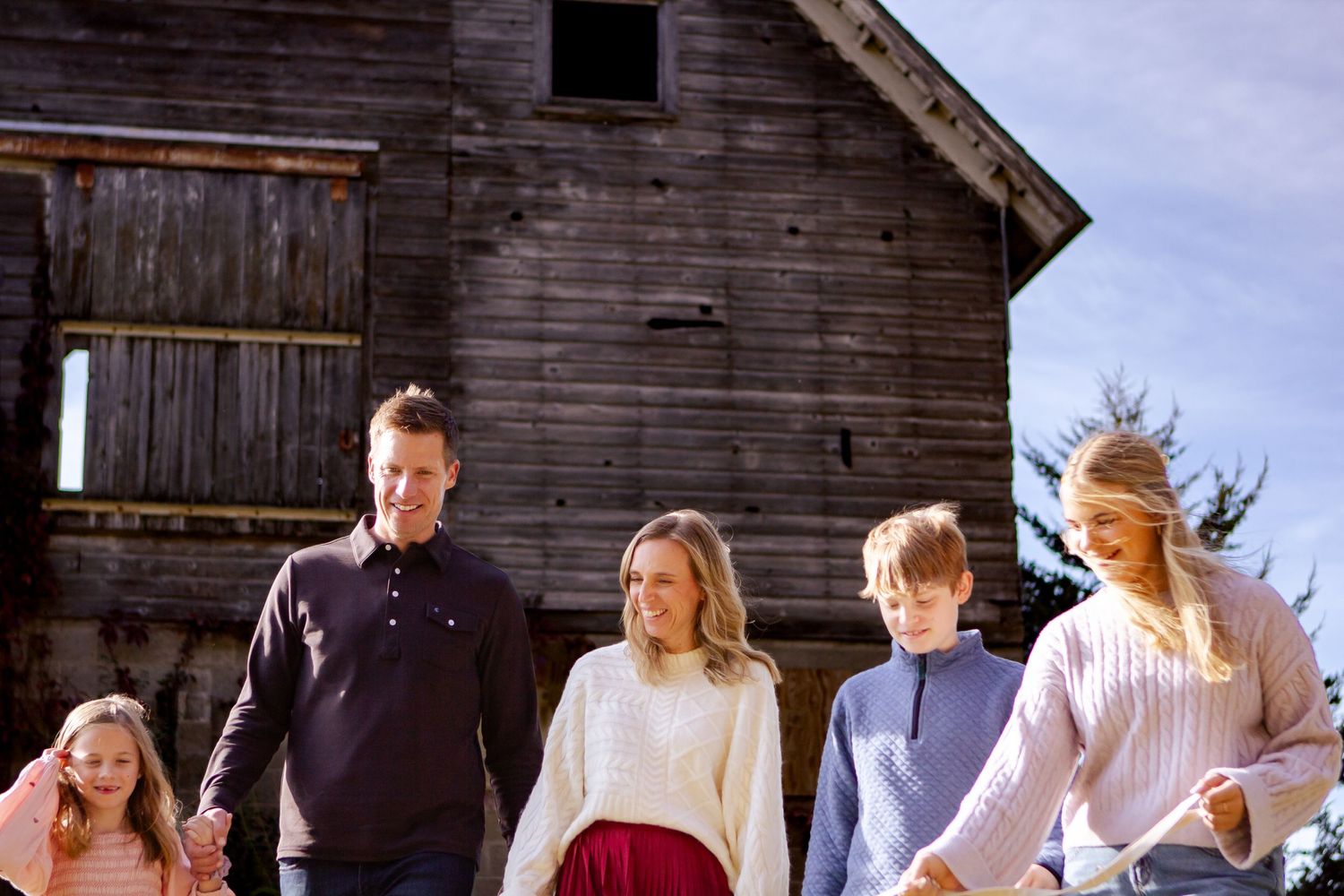 People in traditional dress gather outside rustic wooden buildings at a Lake Country Family session