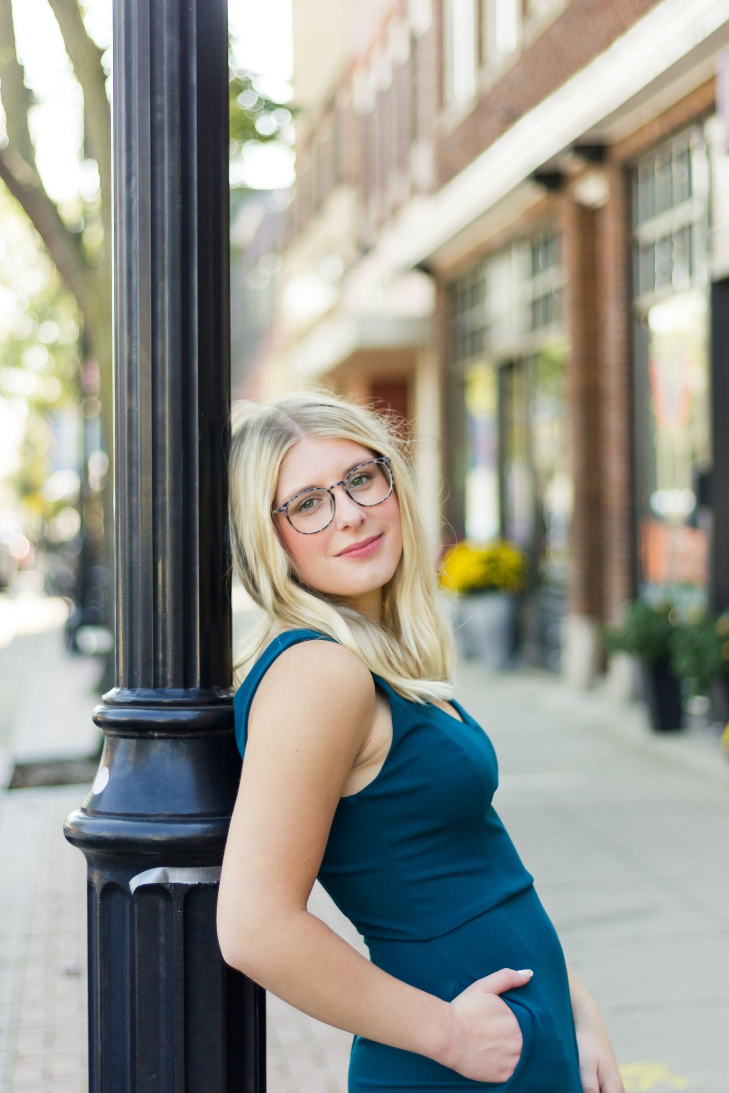 Casual outdoor portrait against a brick building with black metal columns.