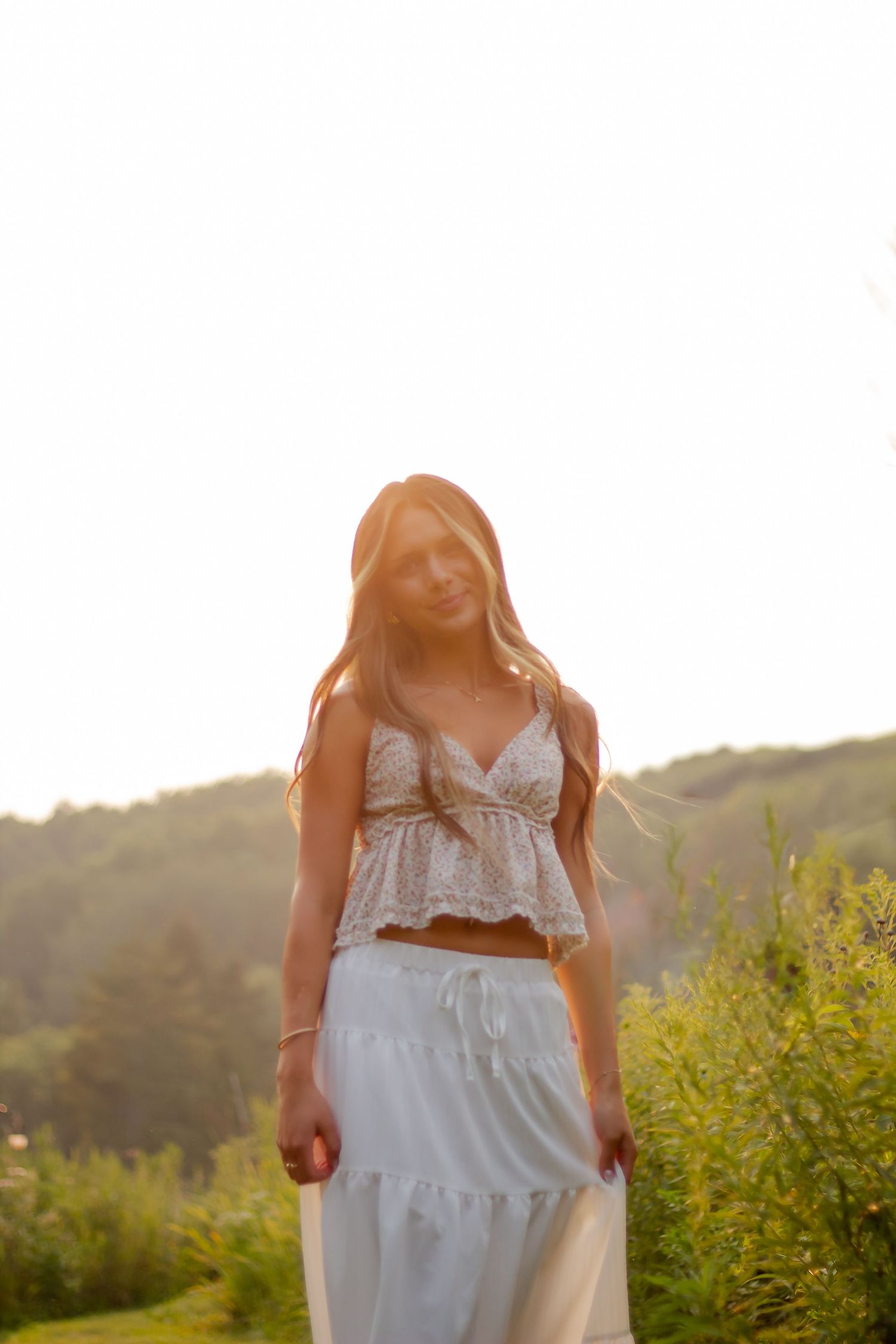 White two-piece dress ensemble captured against natural outdoor backdrop at sunset.