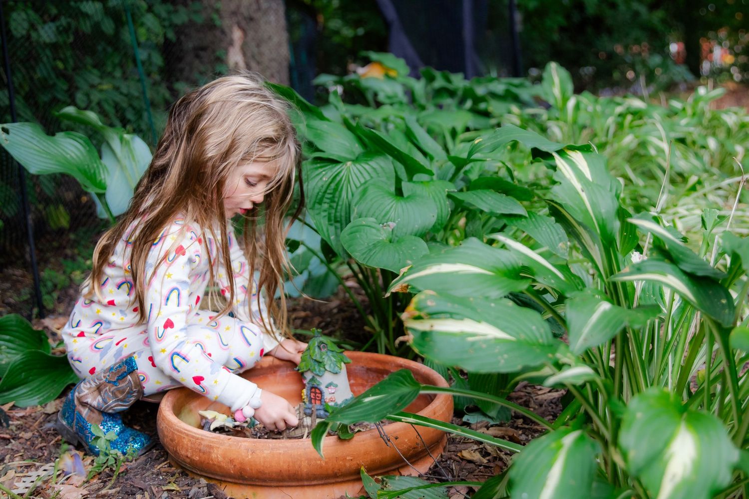 A person in a floral dress tends to potted plants in a lush green garden setting at Delafield home session