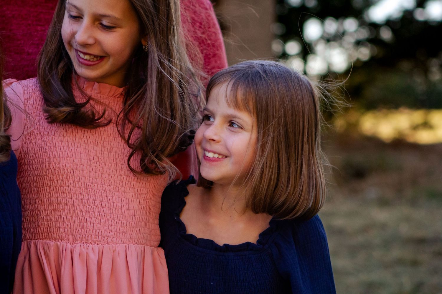 Two people in pink and navy dresses share a joyful moment together outdoors at sunset at an Oconomowoc family session