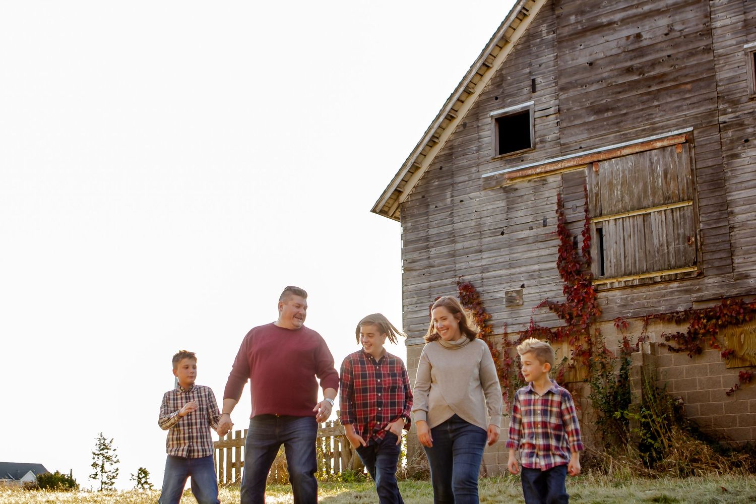 A group walking together in front of a rustic wooden barn during golden hour.