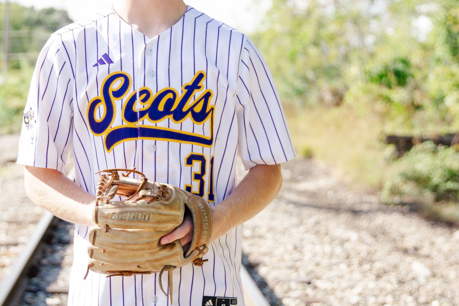 Baseball player poses in pinstripe uniform with glove on field.