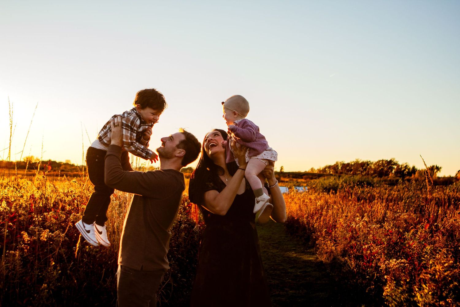 Family enjoying golden hour moments together in a sunlit field at sunset.