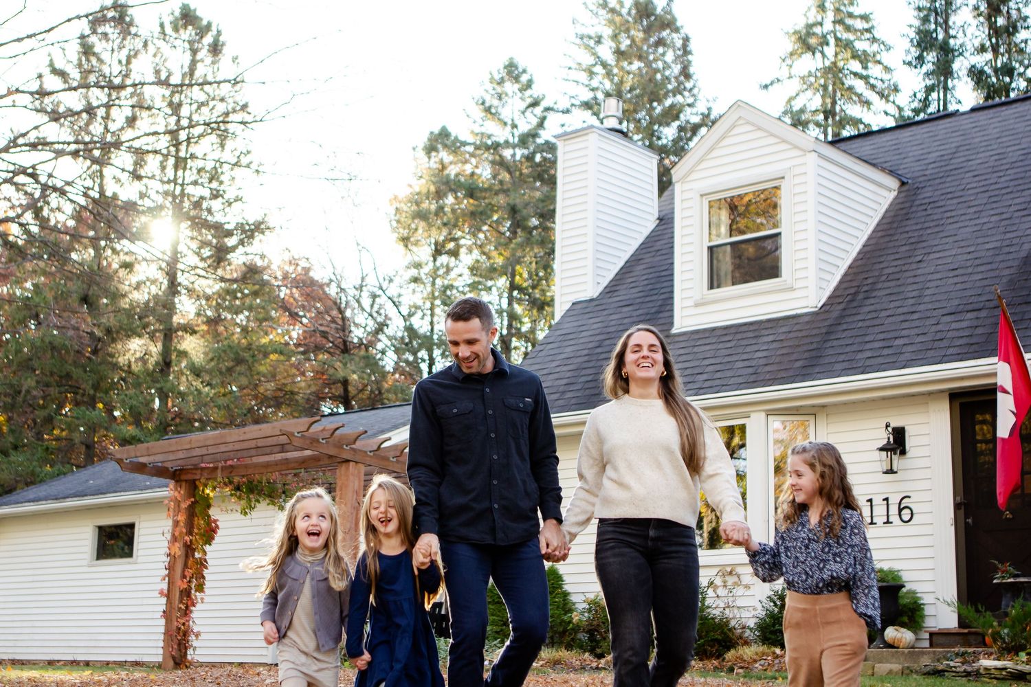 A series of outdoor family photos taken in front of a white house during golden hour lighting.