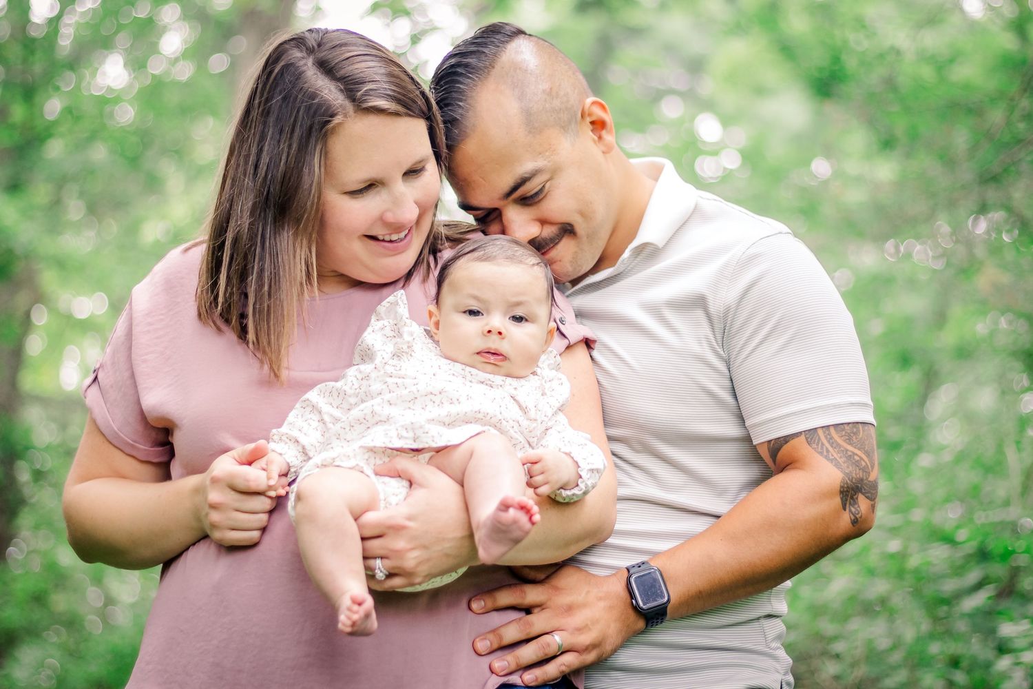 A family shares tender moments together in a lush green outdoor setting during a photo session at Delafield home session