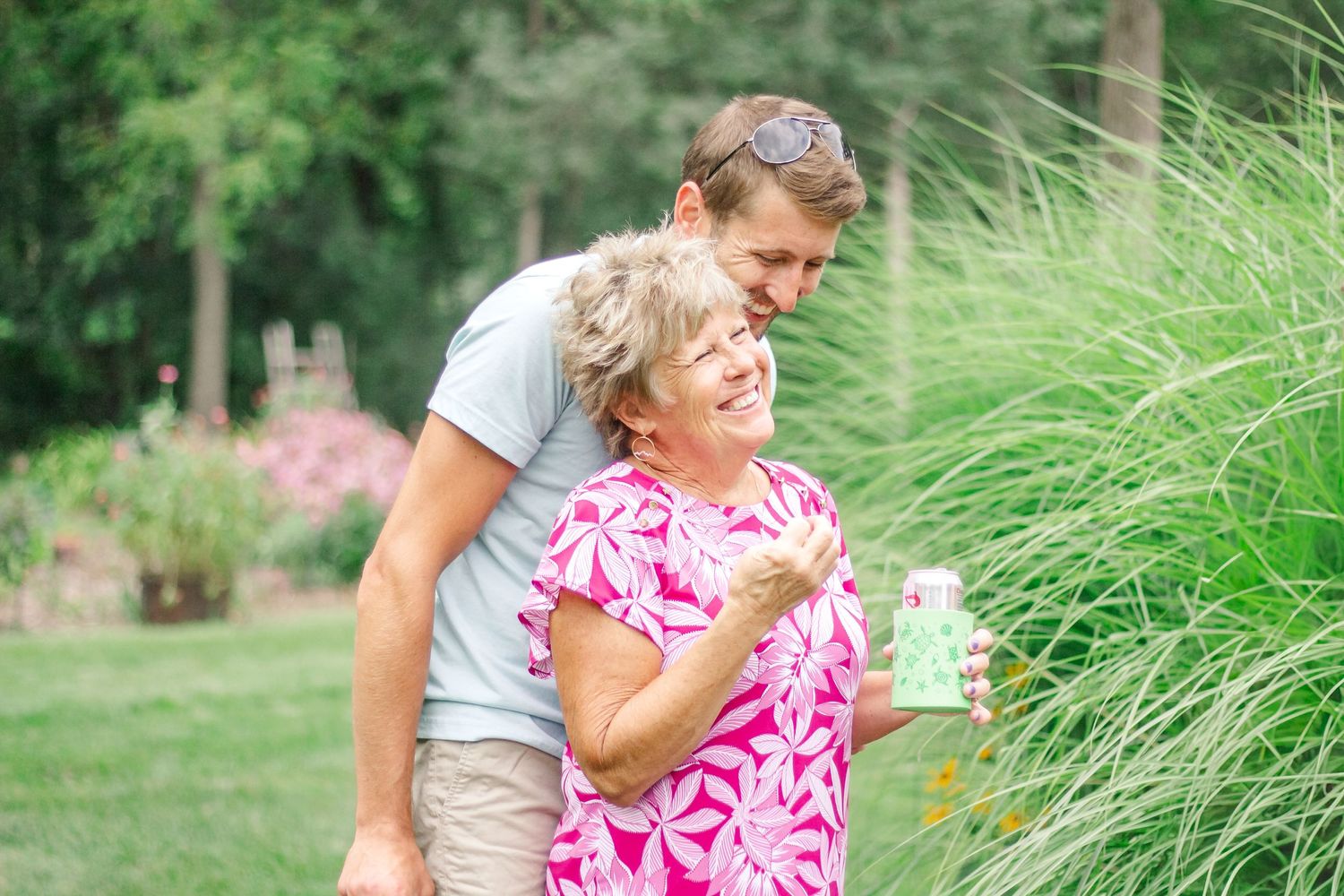 A mother and daughter share a tender moment outdoors in tall grass during a summer photo session at Delafield home session