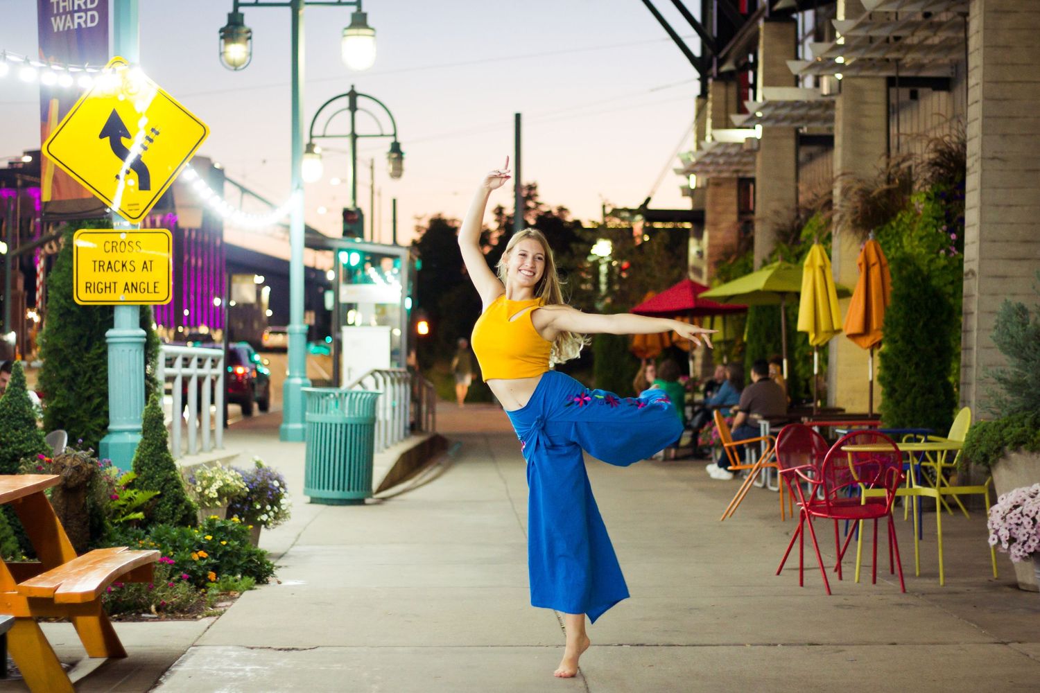Outdoor street scene with blue pedestrian signs and colorful chairs along a walkway.