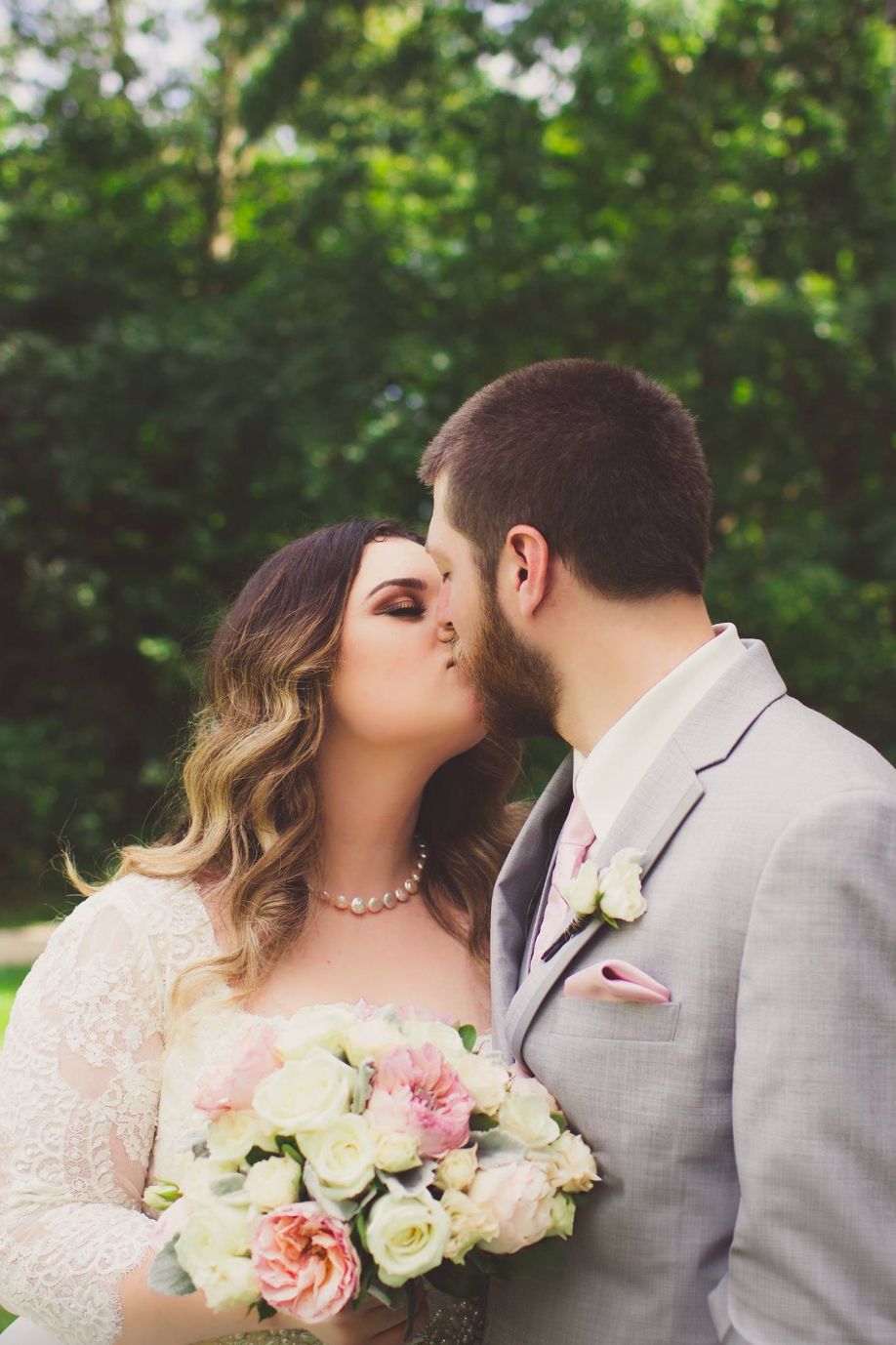 A romantic moment with a bouquet of pink and white roses against a green garden backdrop.