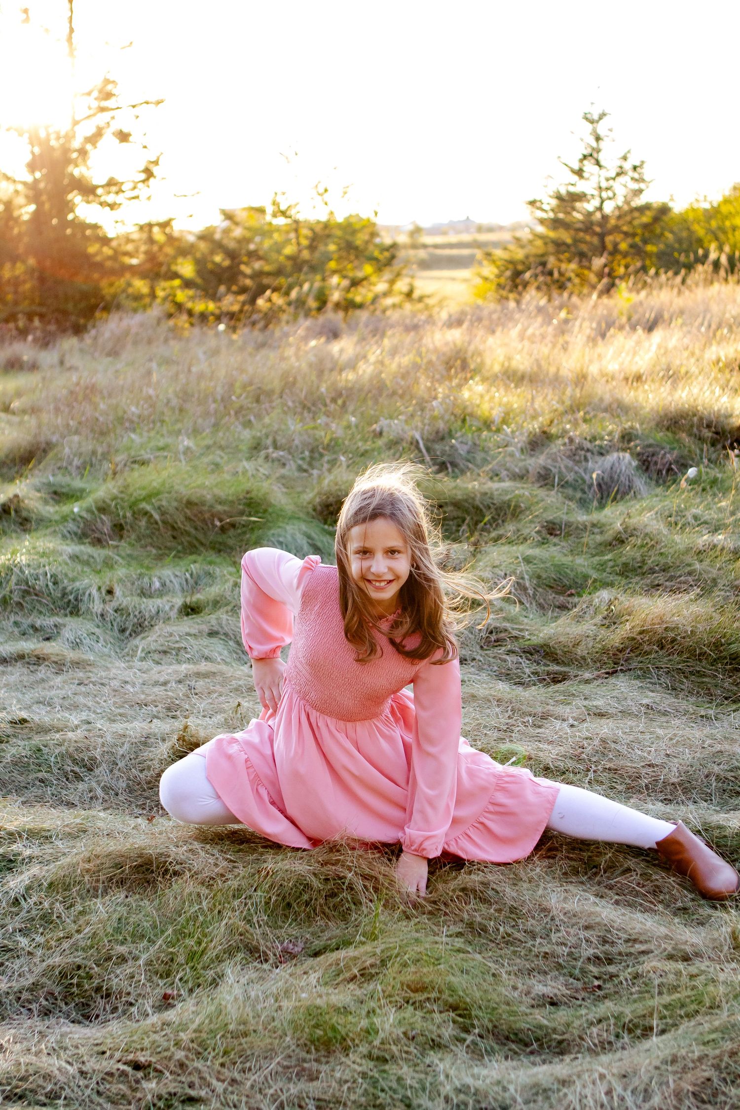 Person in pink dress lying in golden grass field during sunset creating dreamy outdoor portrait at an Oconomowoc family session