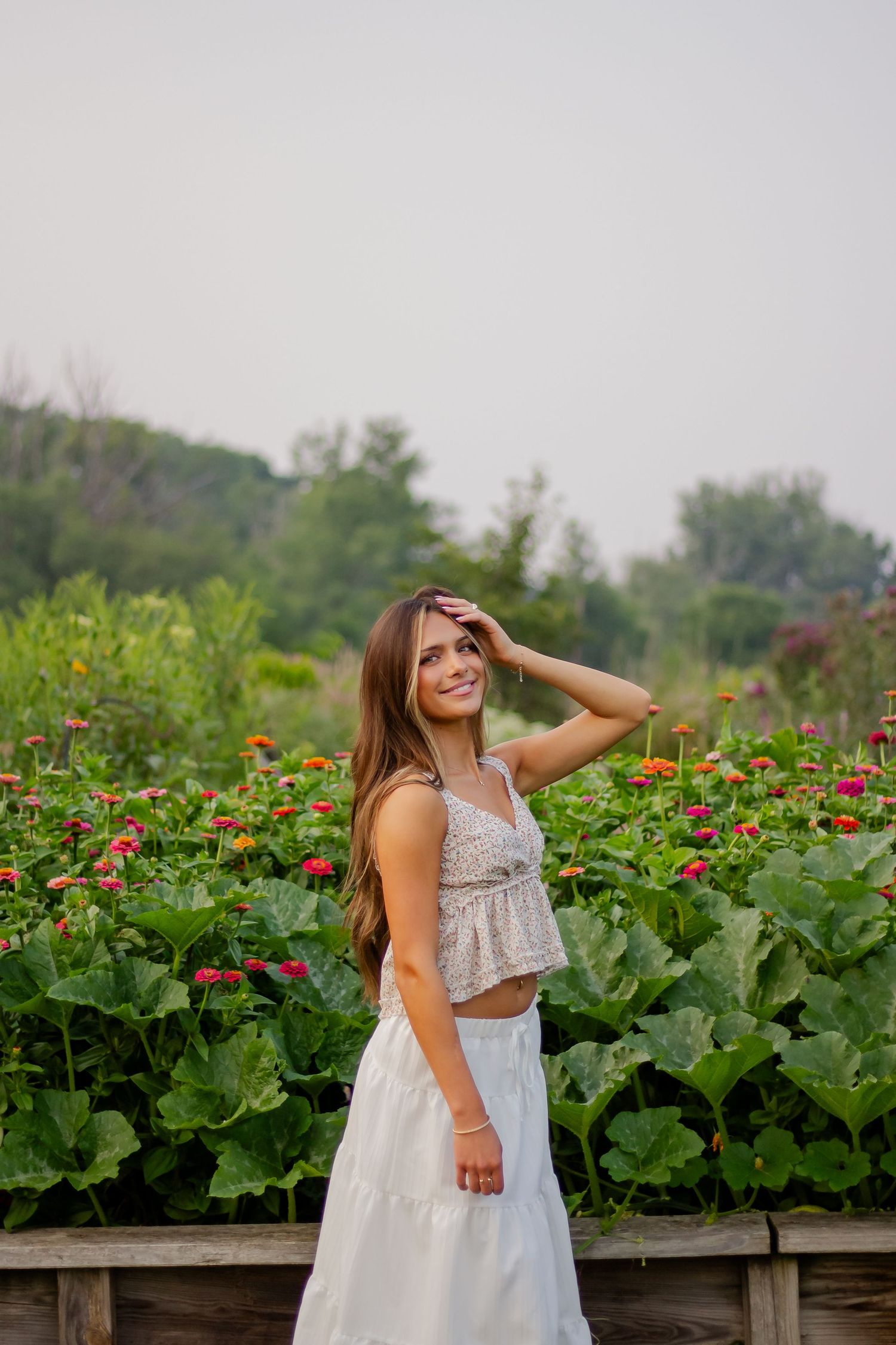 White two-piece outfit styled against garden of blooming red flowers.