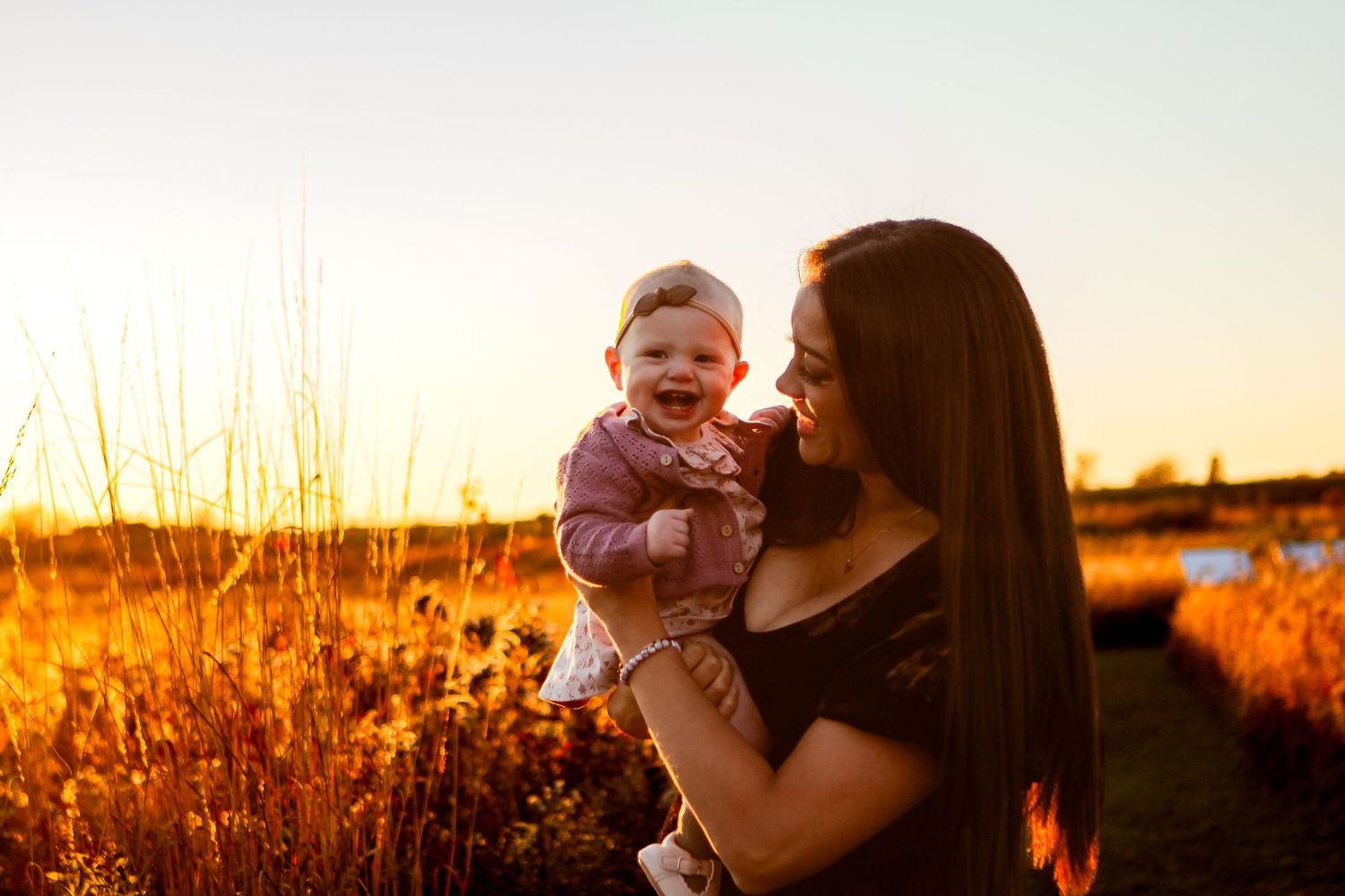 Family embracing in a warm sunset glow against a natural outdoor backdrop.