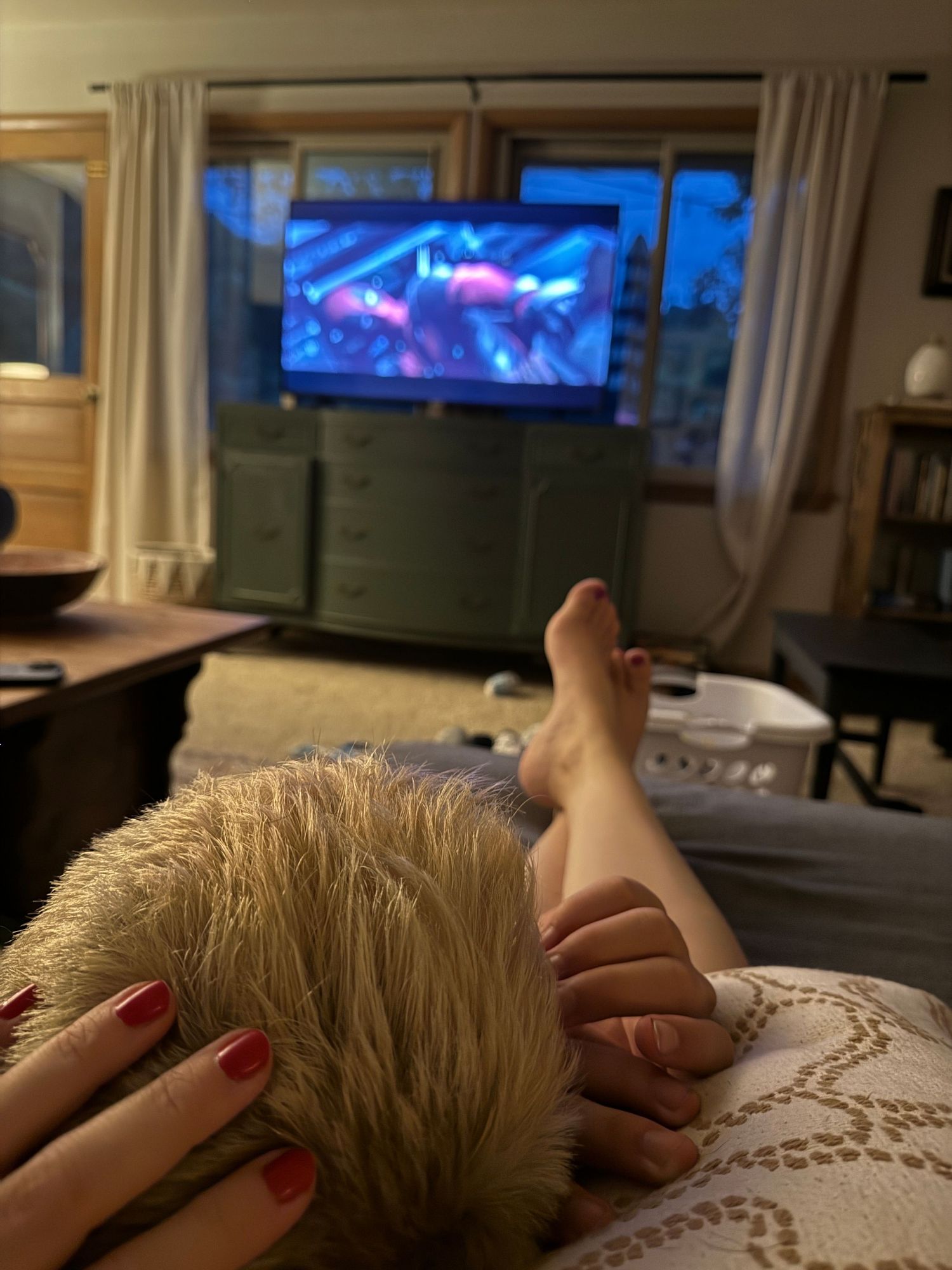 Relaxing view from the couch with feet up and a TV showing colorful content in a cozy living room at dusk at Dousman