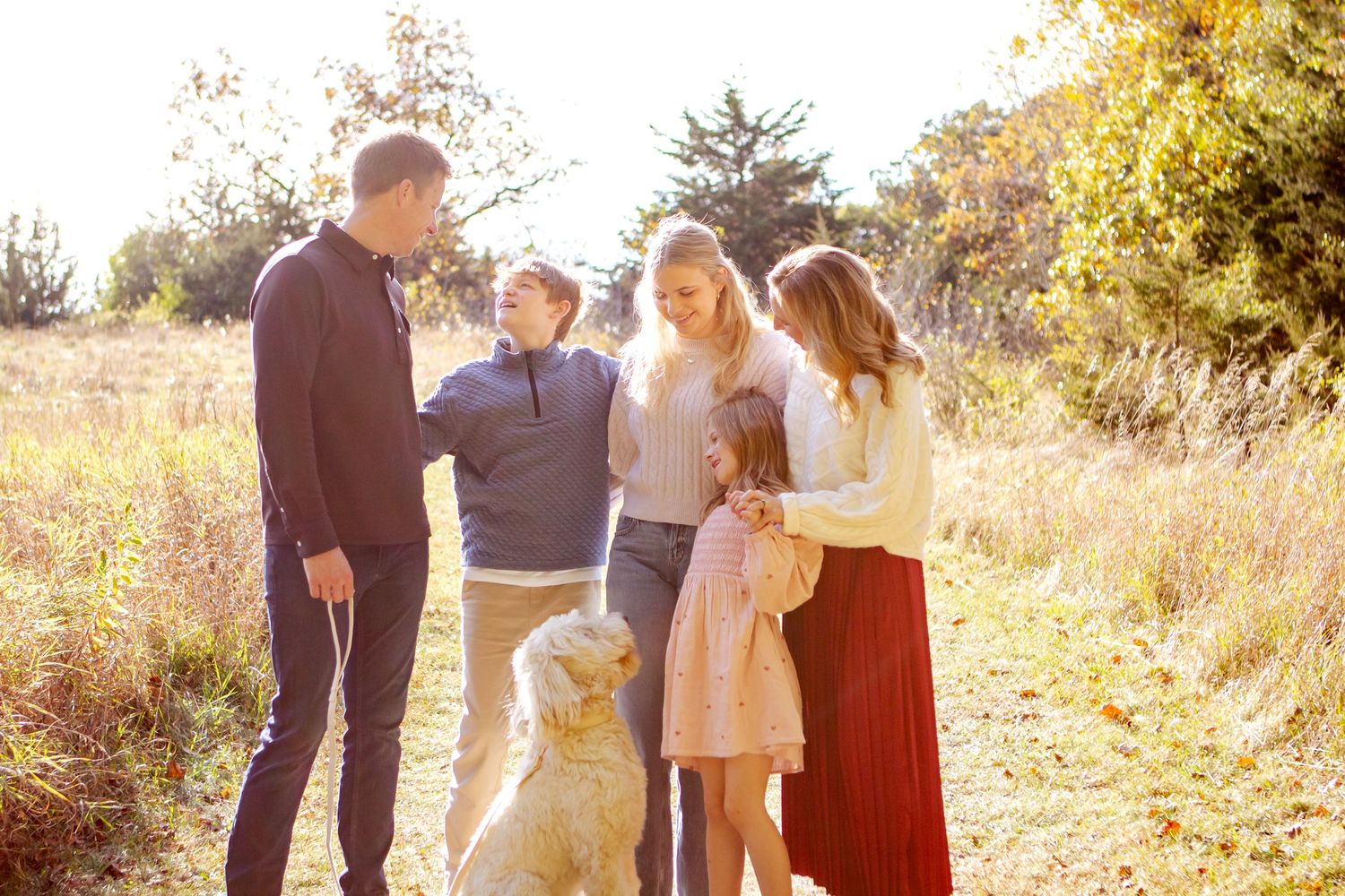 A group gathers outdoors on a sunny autumn day with golden foliage and warm lighting creating a joyful atmosphere in Lake Country
