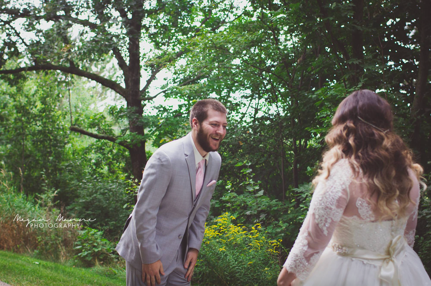 A couple walks together through a lush green garden setting during a wedding photo session.