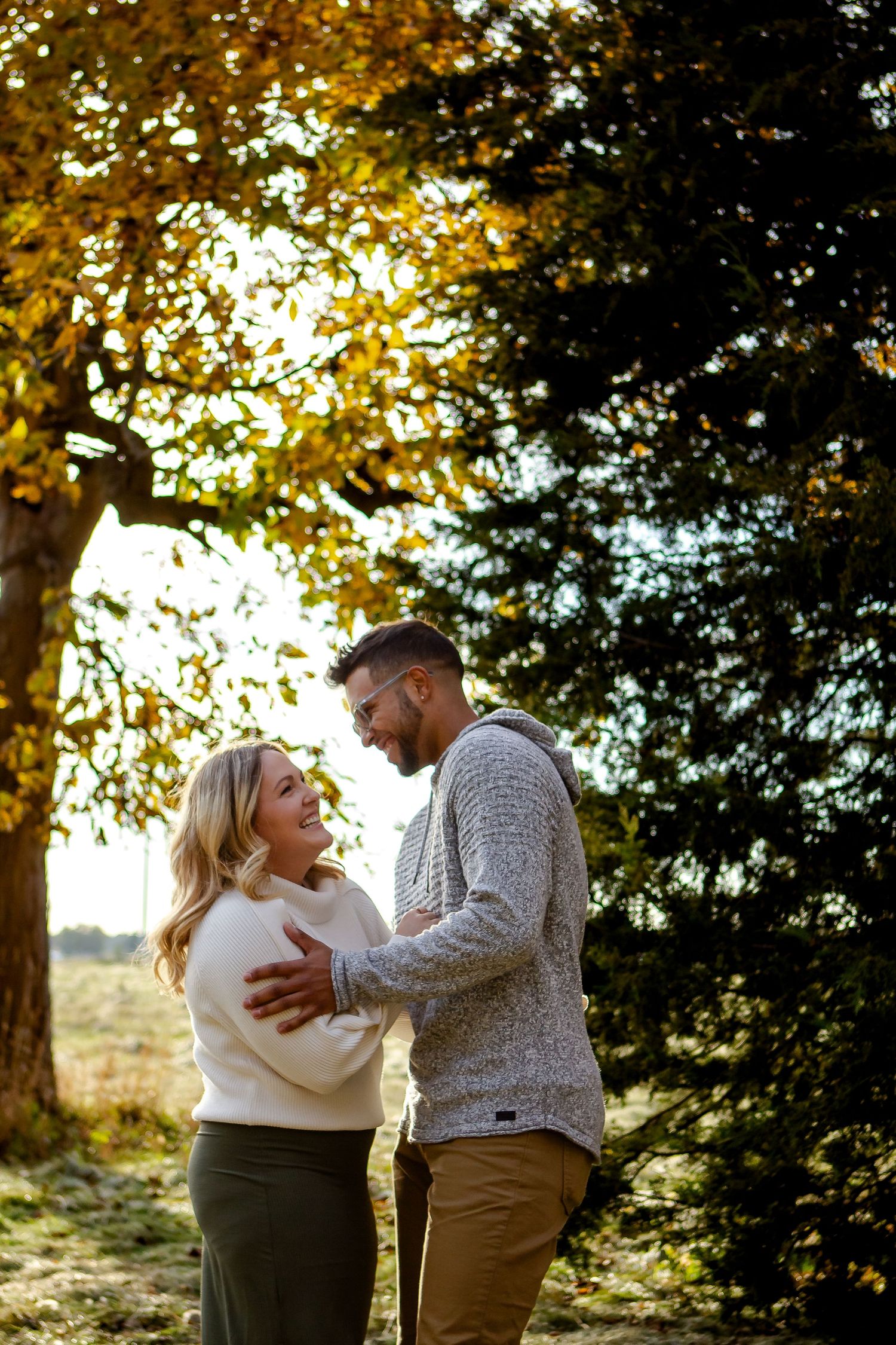 A couple poses by a tree during fall photo session in Oconomowoc