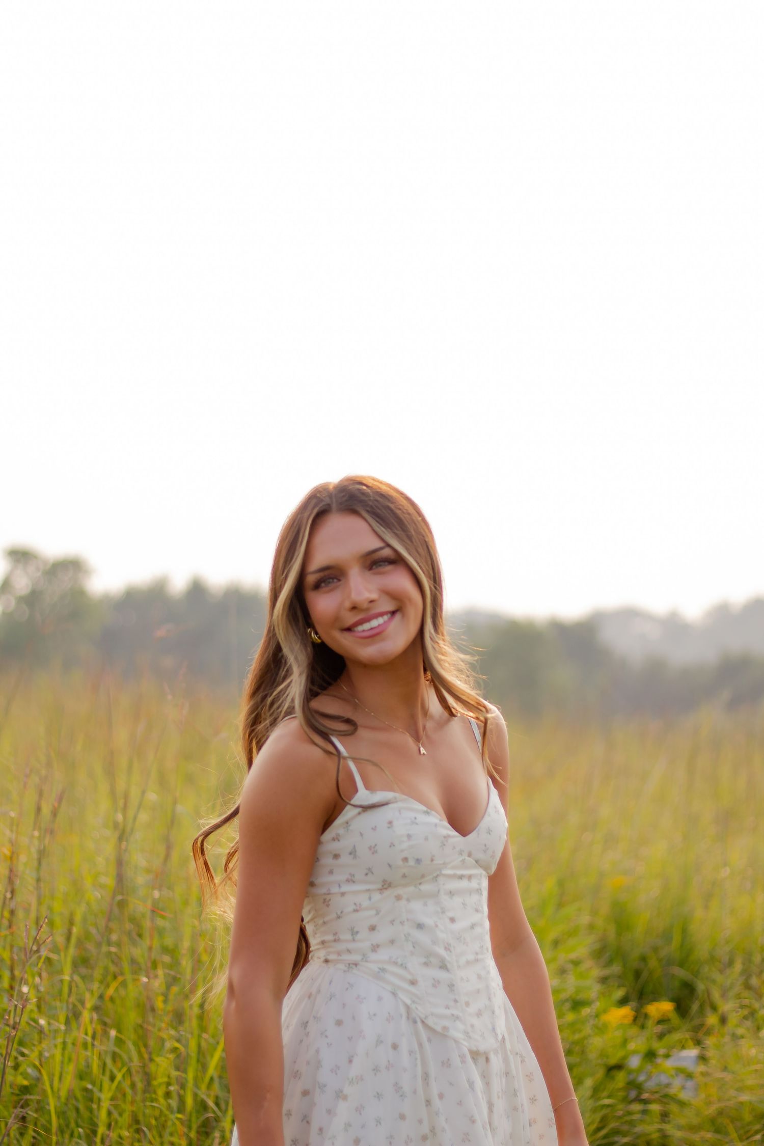 Summer portrait session in a meadow filled with tall grass and golden wildflowers.