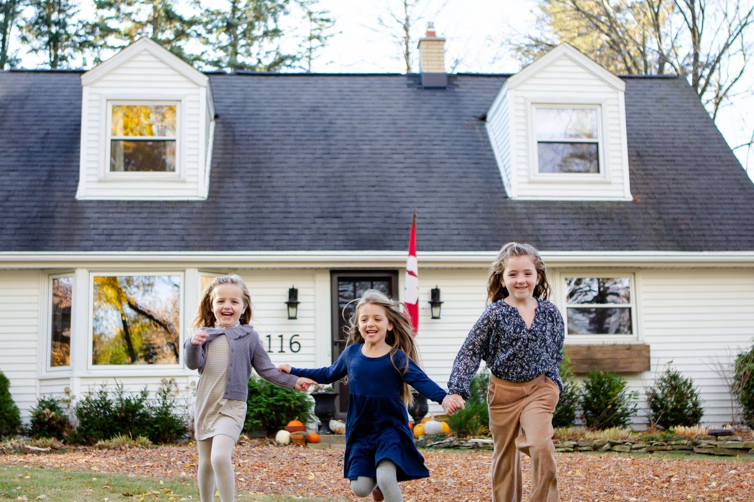 Three sisters run through front yard during fall photo session