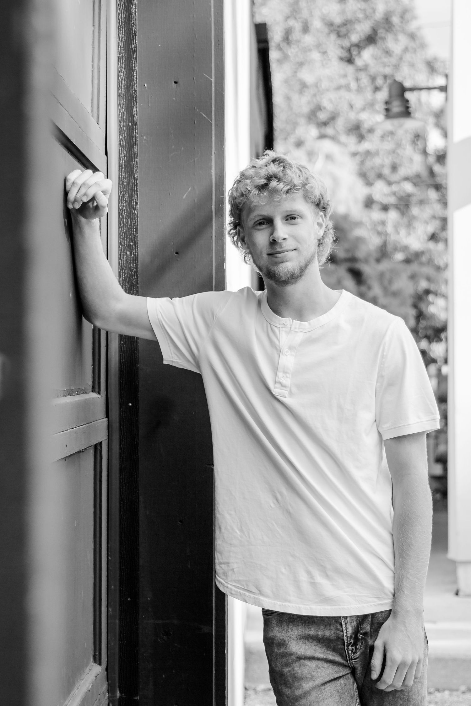 A series of black and white photos showing someone in a white t-shirt and jeans leaning against a doorway in different poses.