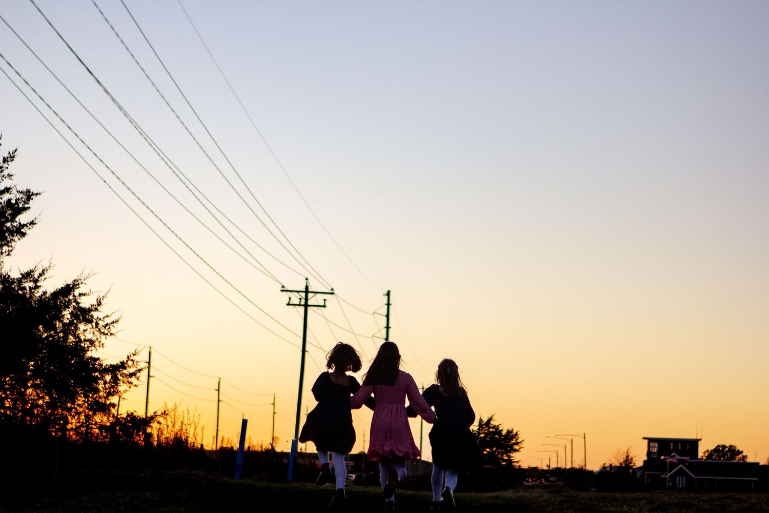 Little girls playing across a colorful sunset sky with orange and purple hues at an Oconomowoc family session
