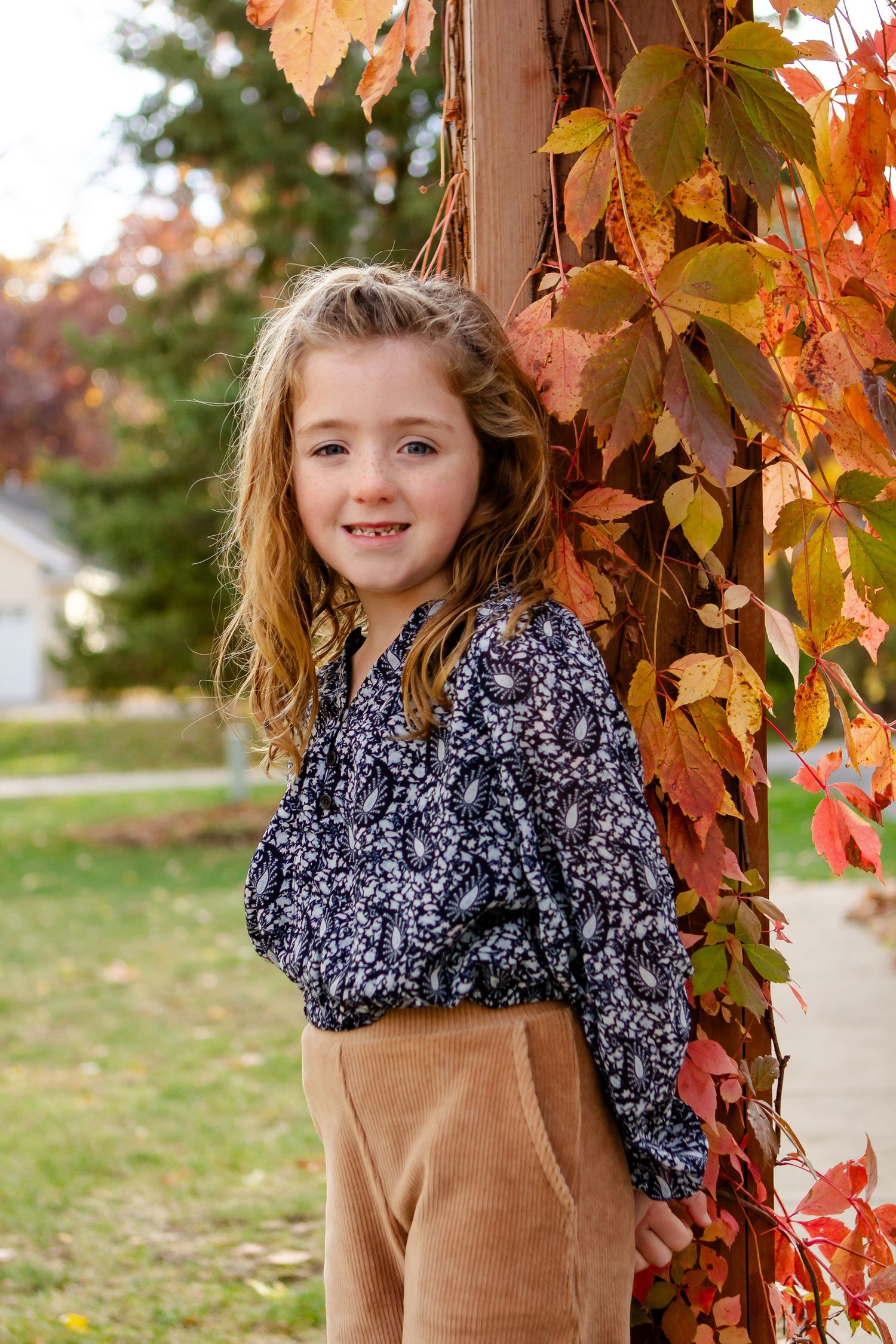 Three autumn photos showing a child in a brown sweater and floral scarf posing near colorful fall foliage by Delafield photographer.