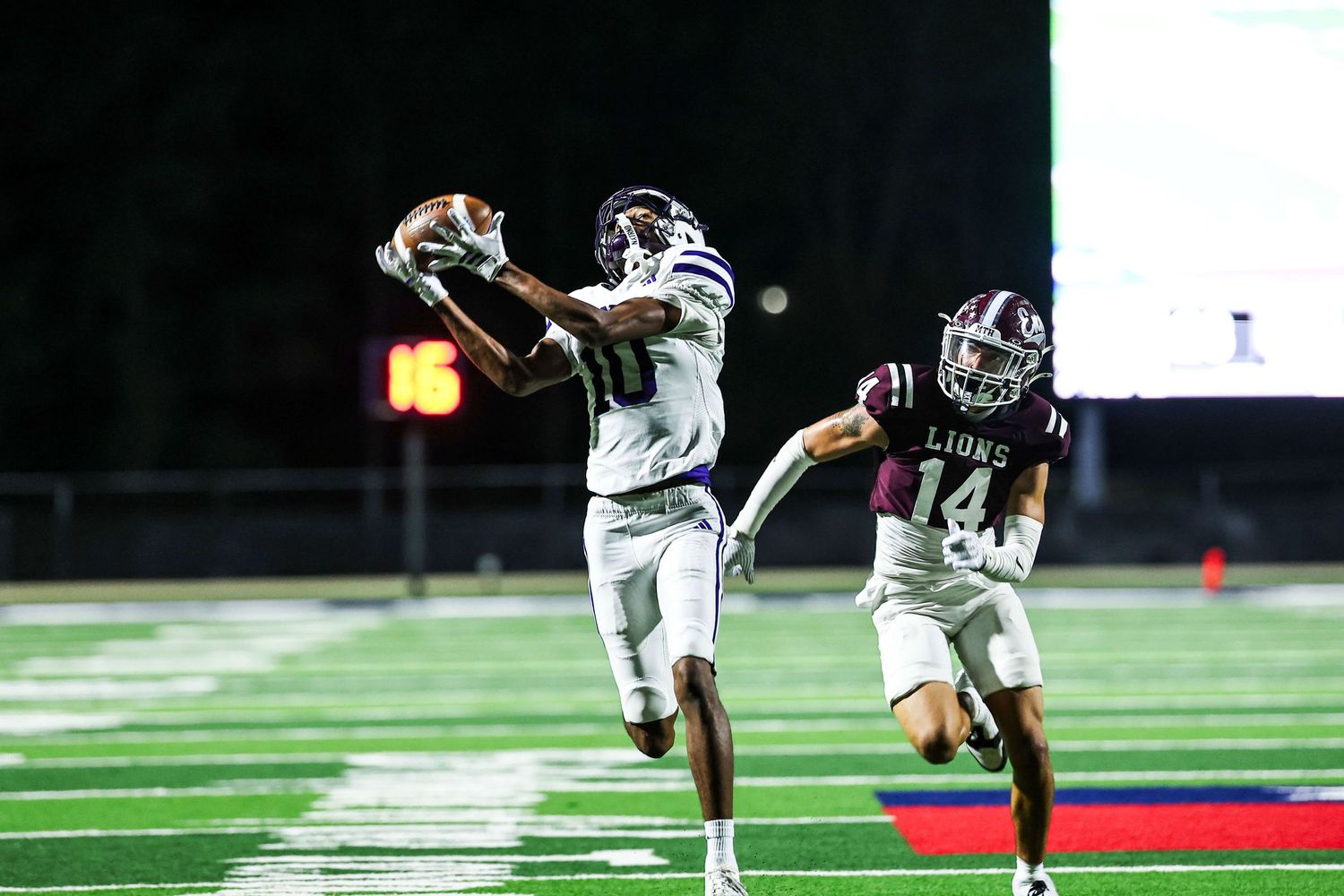 Football players compete on a green field during an intense game.
