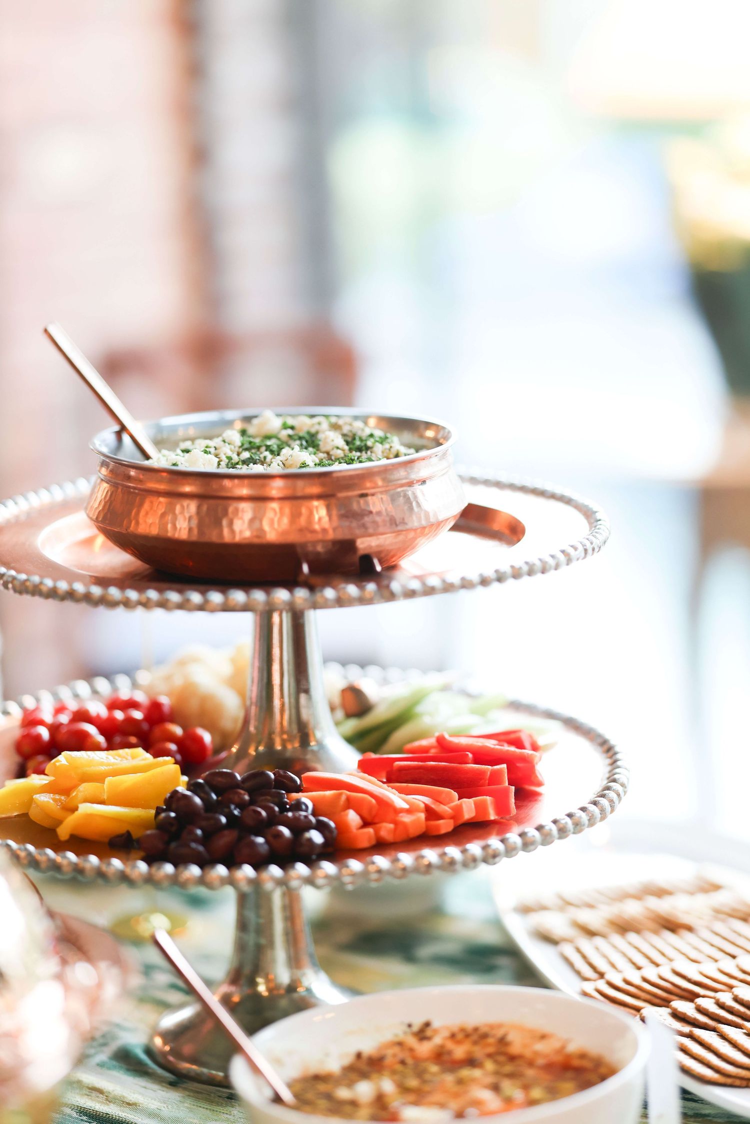 Elegant copper serving platters and stands display colorful appetizers and snacks at an upscale party spread.
