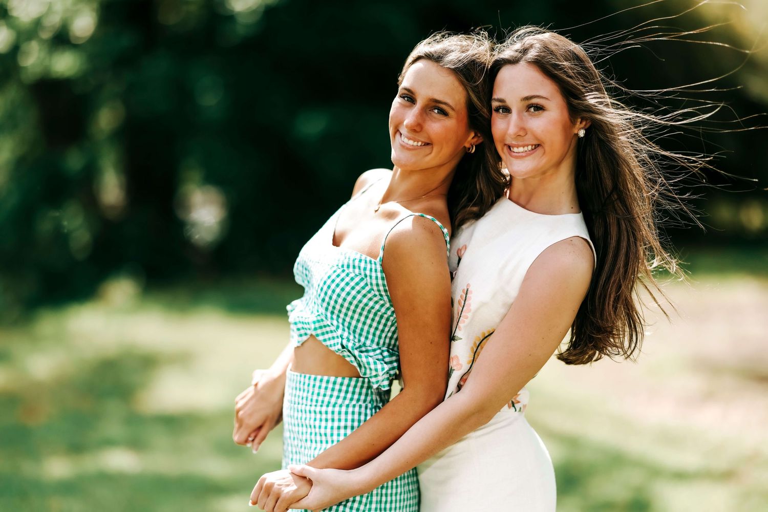 Mother and daughter in matching outfits embracing outdoors on sunny day.