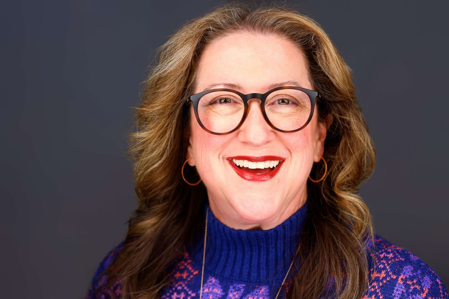Studio portraits of women in colorful sweaters smiling against dark backdrop.