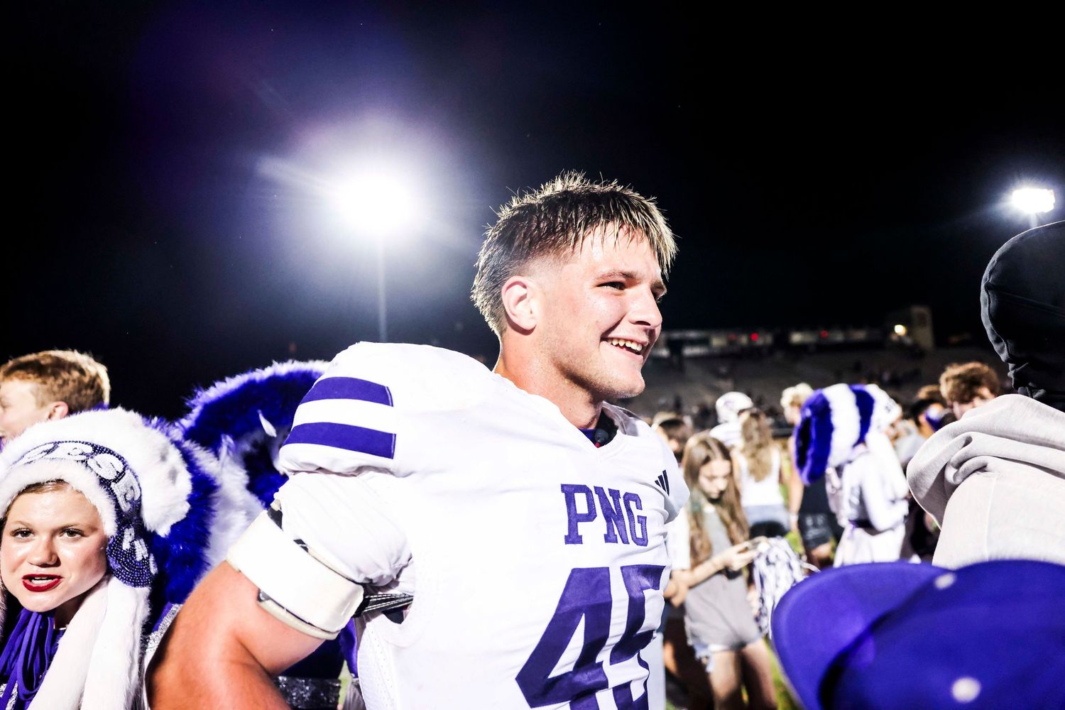 Football player celebrates during nighttime victory celebration.