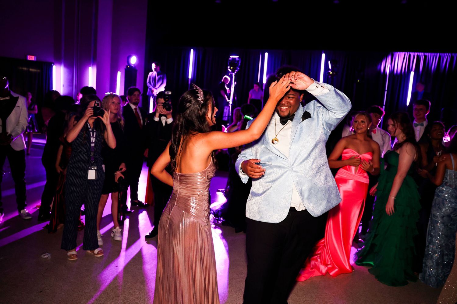 People dancing at a nightclub with purple lighting and neon accents creating an energetic party atmosphere.