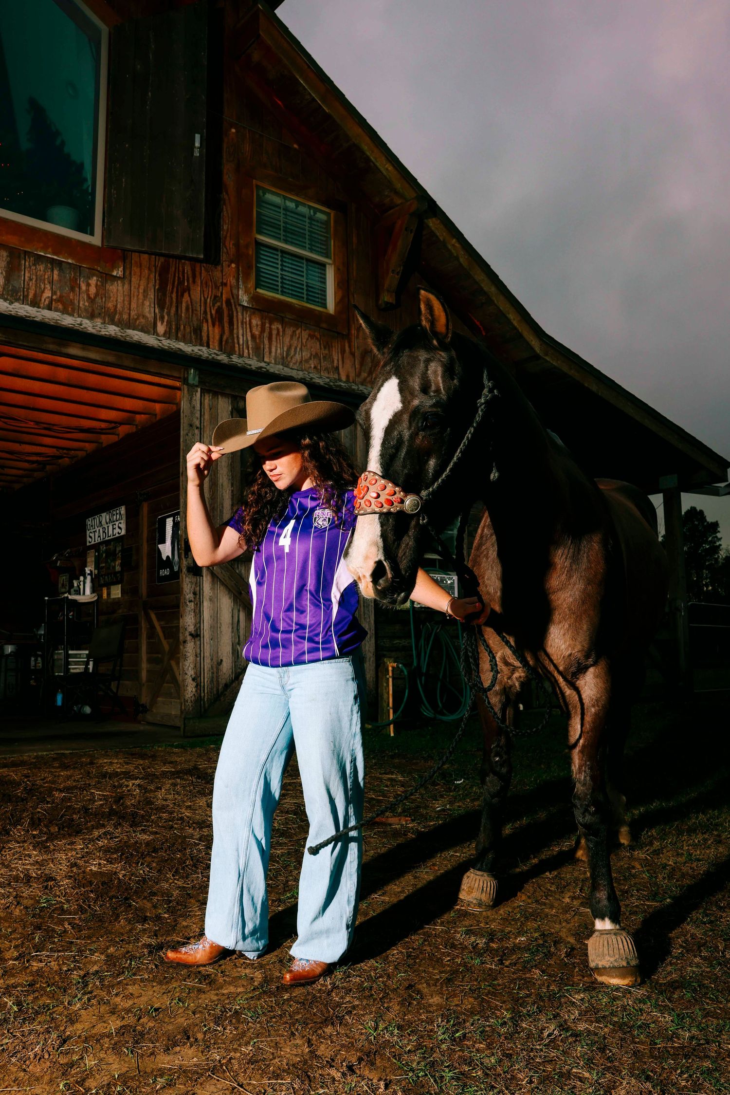 Rural photoshoot scene with horses and people in casual western attire at a barn.