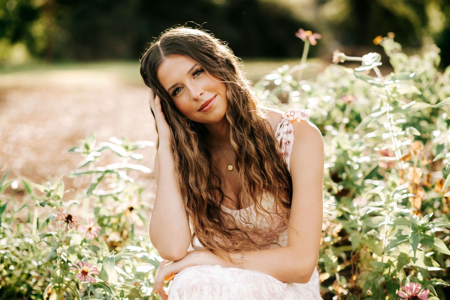 Woman in floral setting poses with natural lighting and garden backdrop.