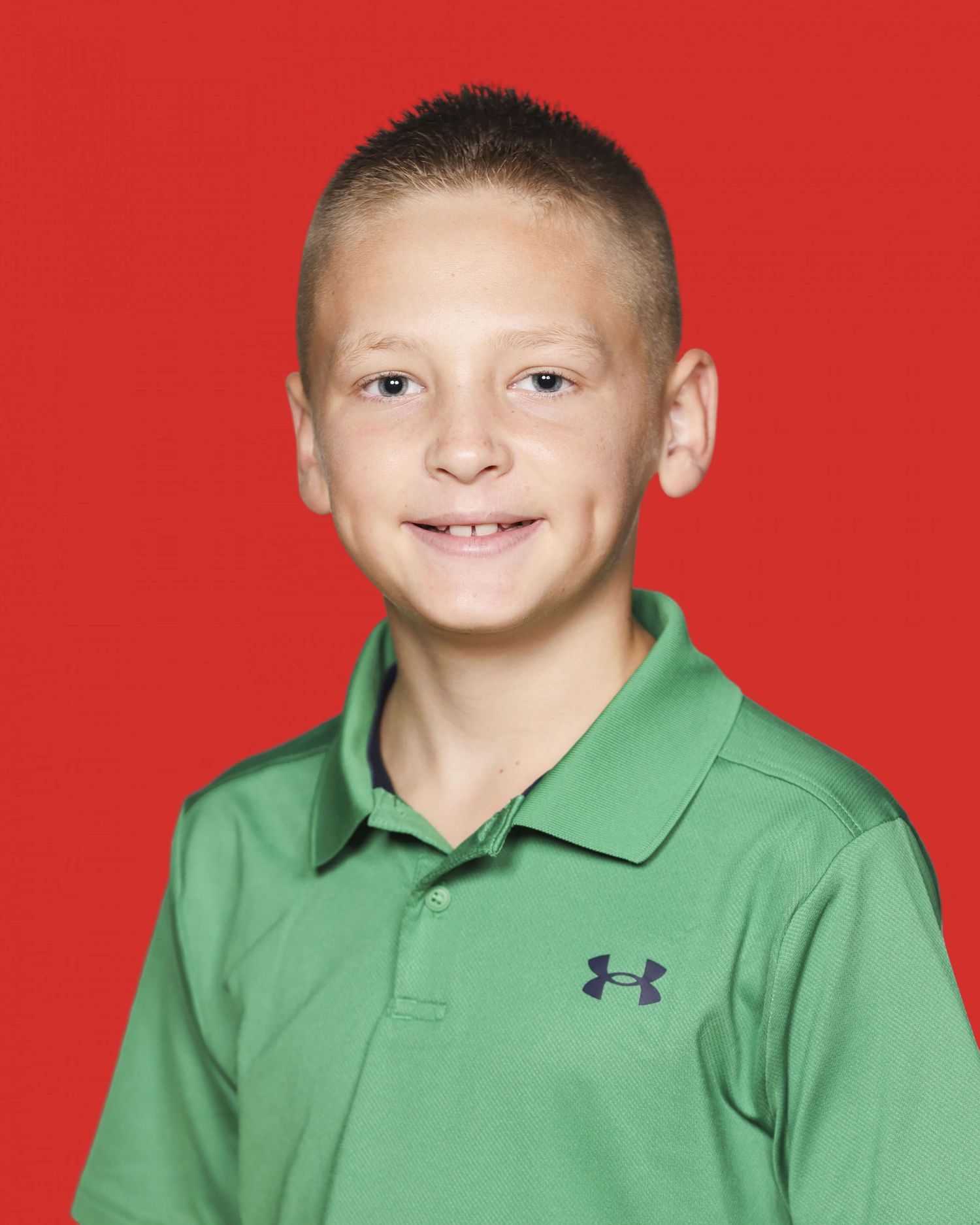Student portrait against a red background wearing a green Under Armour polo shirt.