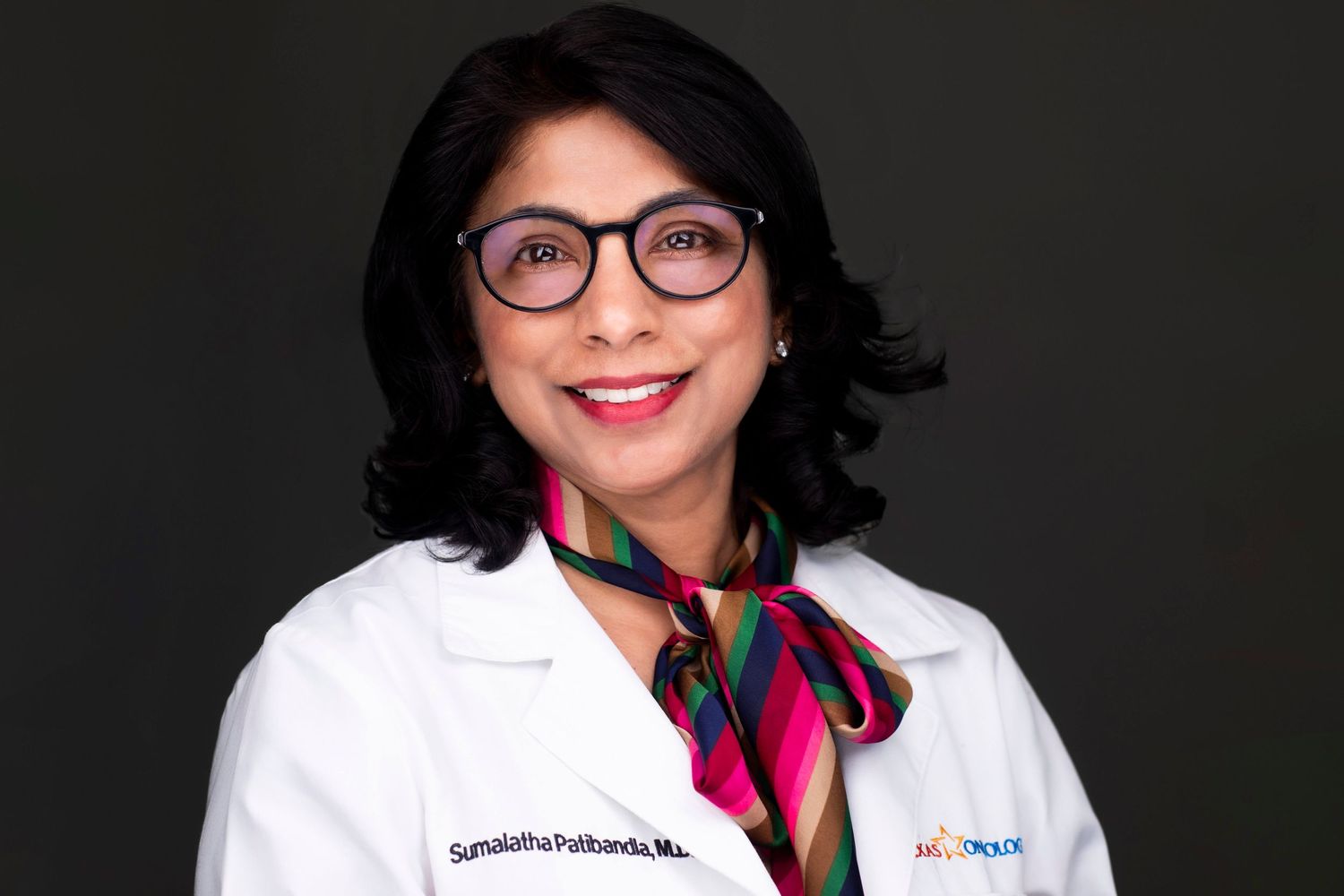 Medical professionals in white coats and glasses posing for headshots against dark background.