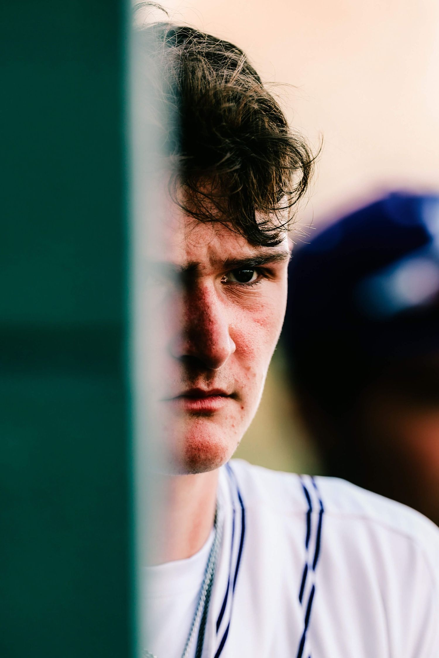Close-up side profile shot of baseball player in dugout wearing pinstripe uniform.