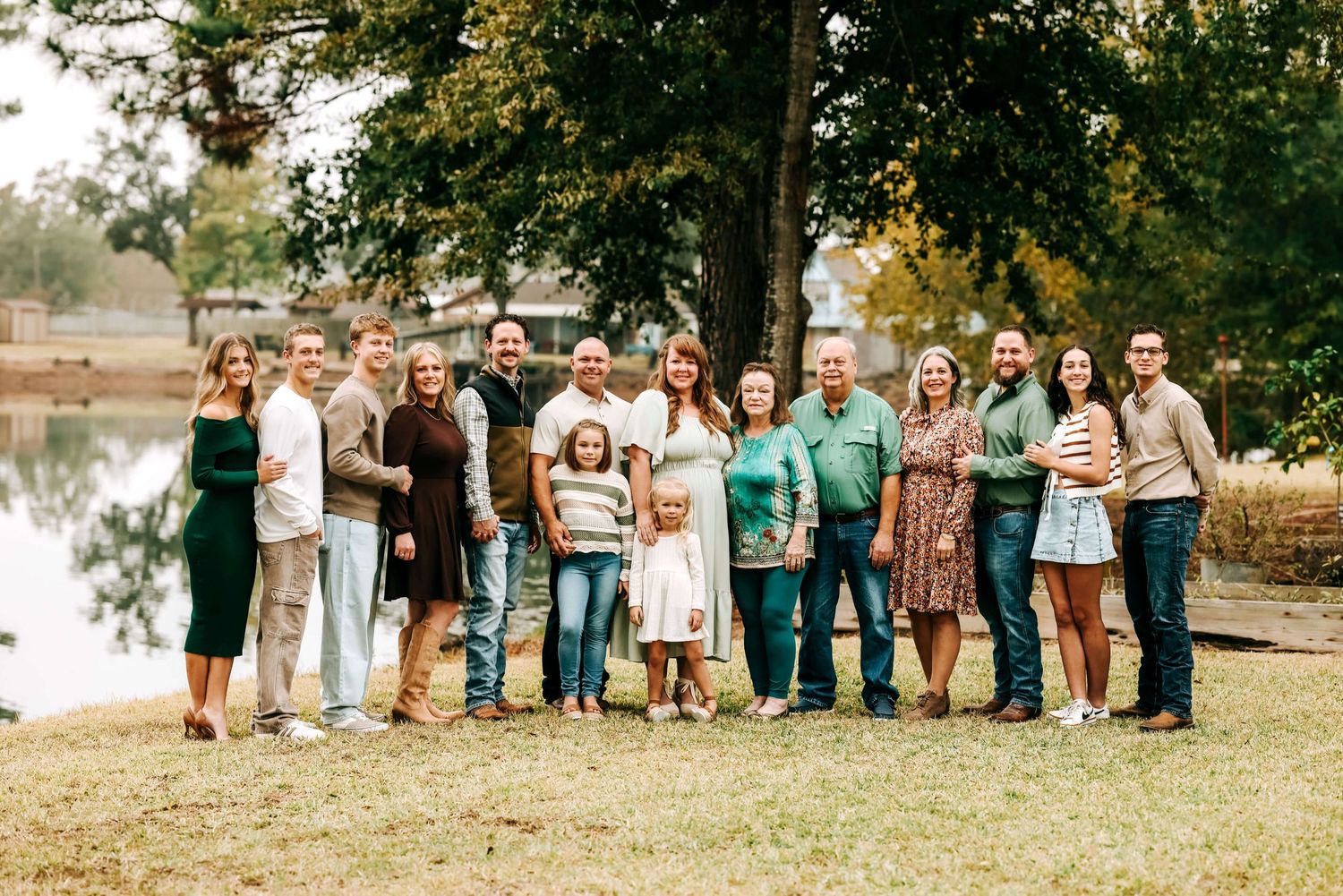 Large group of people standing together for a photo by a lake on an autumn day.