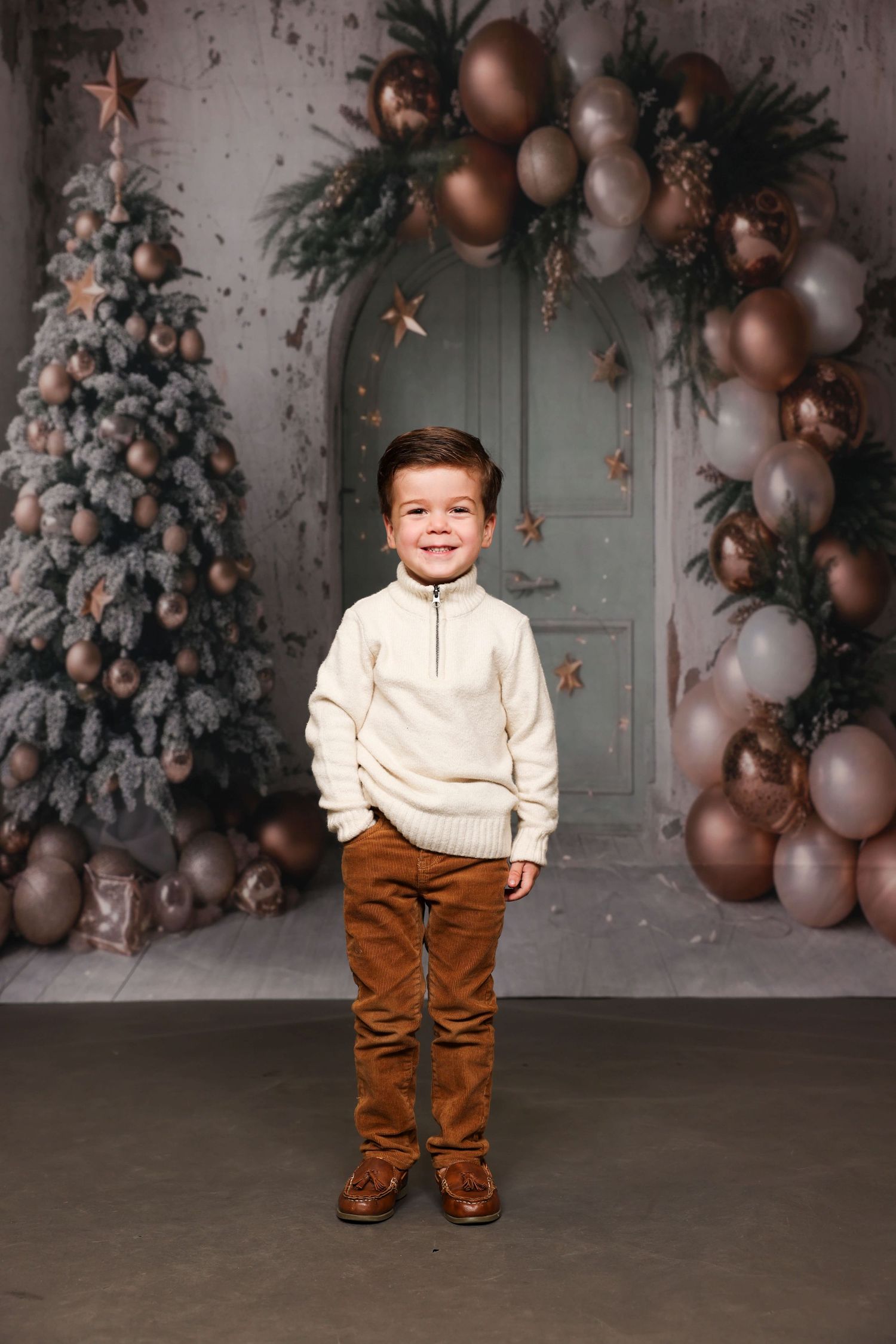 Holiday photo setup with decorated Christmas tree, balloons, and festive decor against vintage door.
