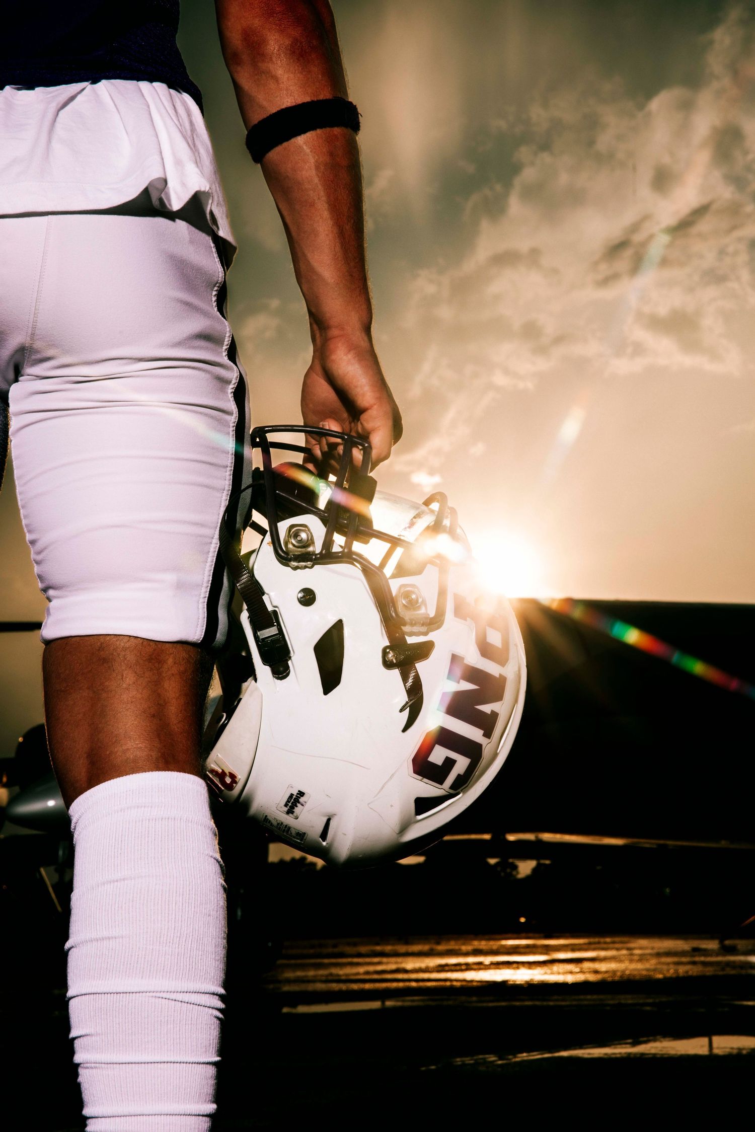 Close-up of football players in white uniforms against dramatic sunset sky.